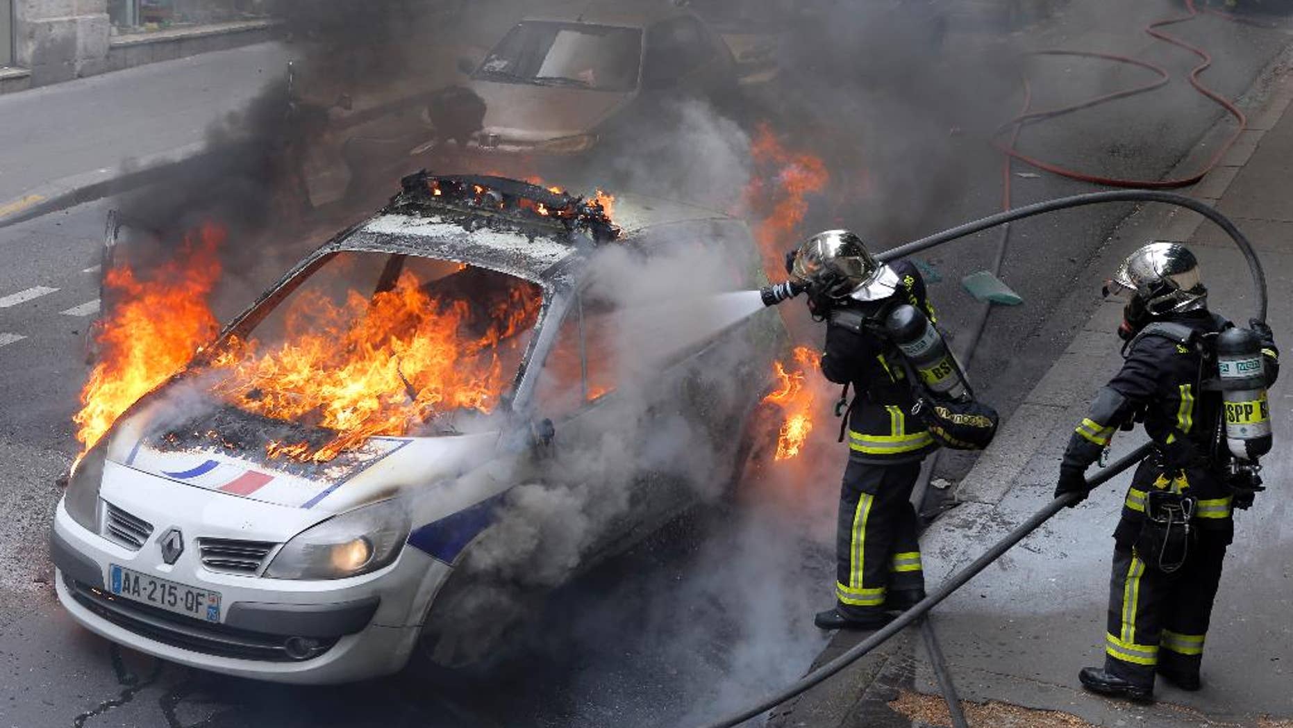 May 18, 2016: Firefighters work on a police car set up on fire by counter demonstrators while police forces gather to denounce the almost daily violent clashes at protests against a labor reform in Paris.