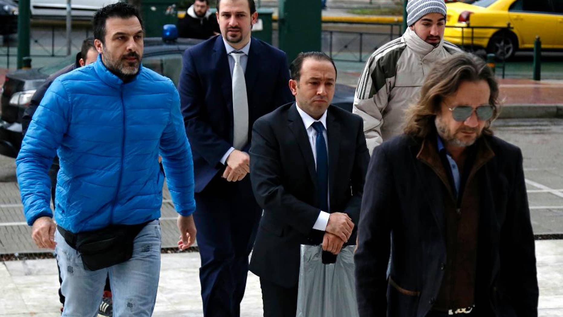 Two Turkish military officers wearing handcuffs, center, escorted by plain-clothed police officers arrive at the Supreme Court in Athens, on Wednesday, Jan. 11, 2017. A prosecutor at Greece's highest court recommended on Tuesday the court reject an extradition request for two other Turkish servicemen, who fled to Greece after a failed July military coup in their country. (Stelios Misinas/Eurokinissi via AP)