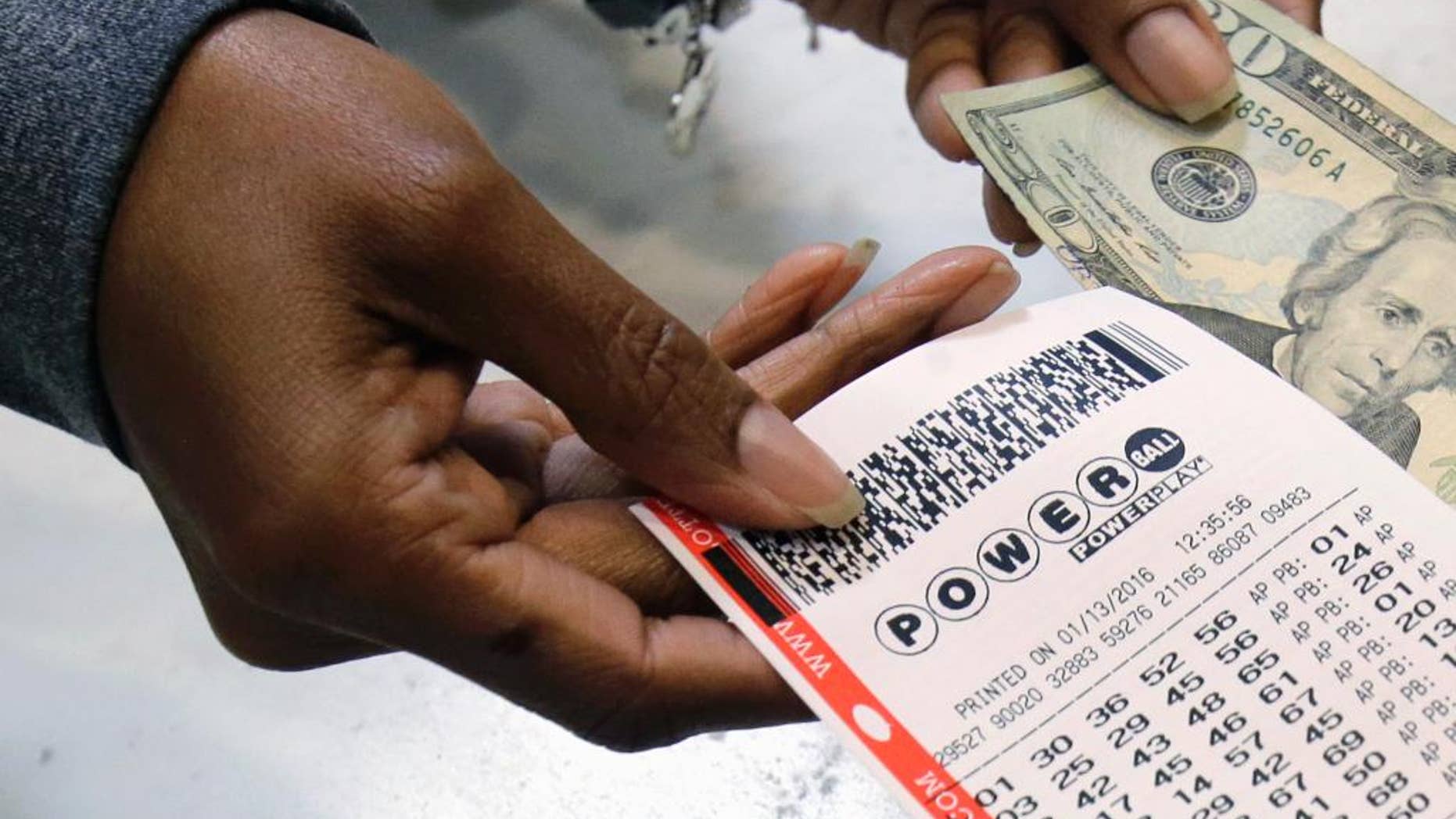 FILE - In this Jan. 13, 2016 file photo, a clerk hands over a Powerball ticket for cash at Tower City Lottery Stop in Cleveland. Powerball estimates that its jackpot for the May 4, 2016, drawing is $348 million. (AP Photo/Tony Dejak, File)