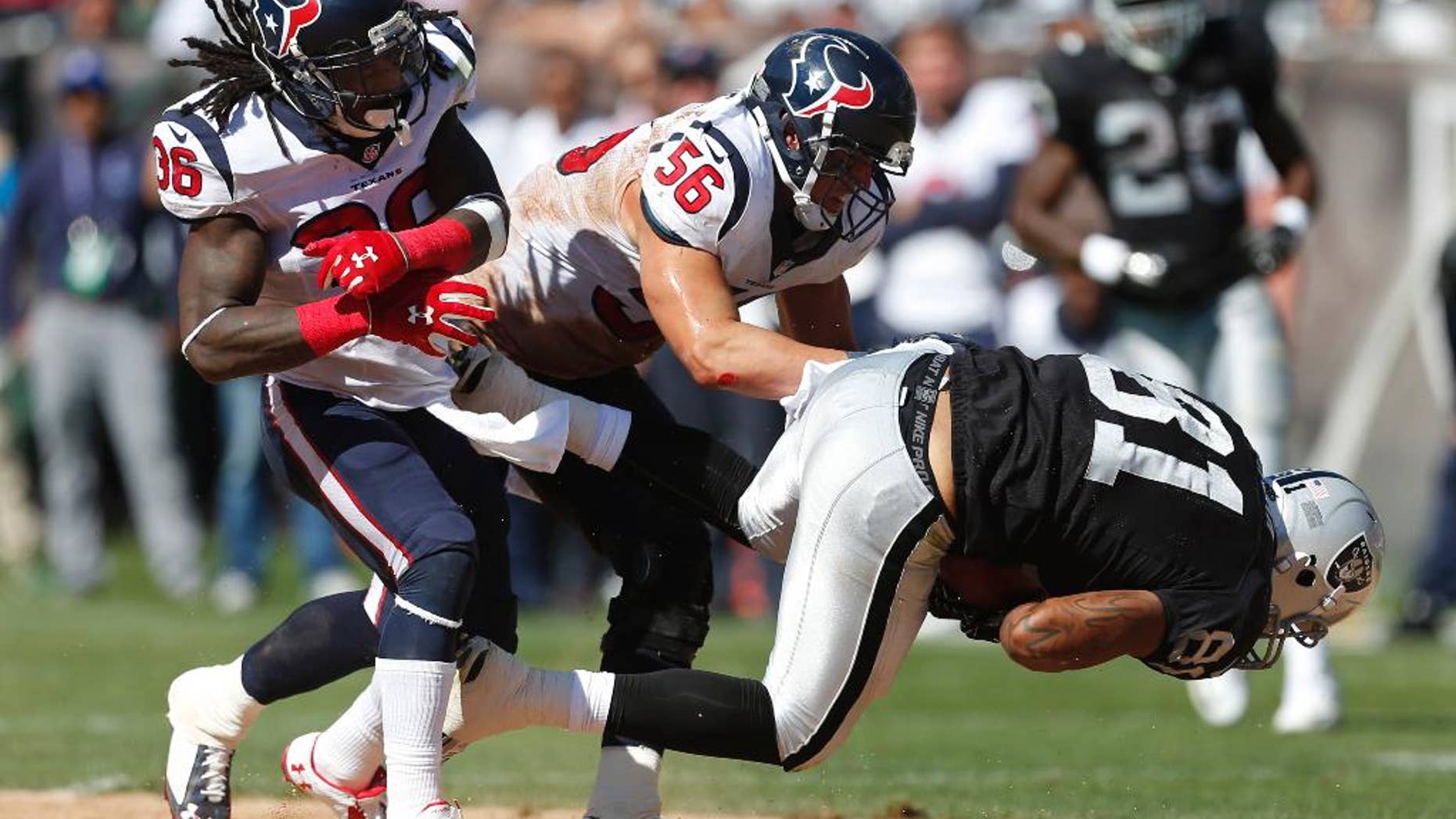 Oakland Raiders tight end Mychal Rivera, right, is brought down with the ball by Houston Texans inside linebacker Brian Cushing (56) as Texans strong safety D.J. Swearinger (36) looks on in the third quarter of an NFL football game Sunday, Sept. 14, 2014, in Oakland, Calif. (AP Photo/Beck Diefenbach)