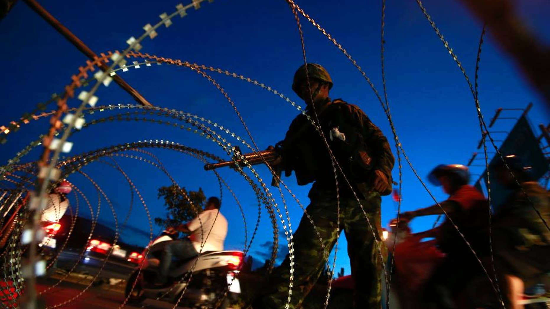 May 20, 2014: A Thai soldier mans a checkpoint as motorcyclists ride past near the site where pro-government demonstrators stage a rally on the outskirts of Bangkok, Thailand.