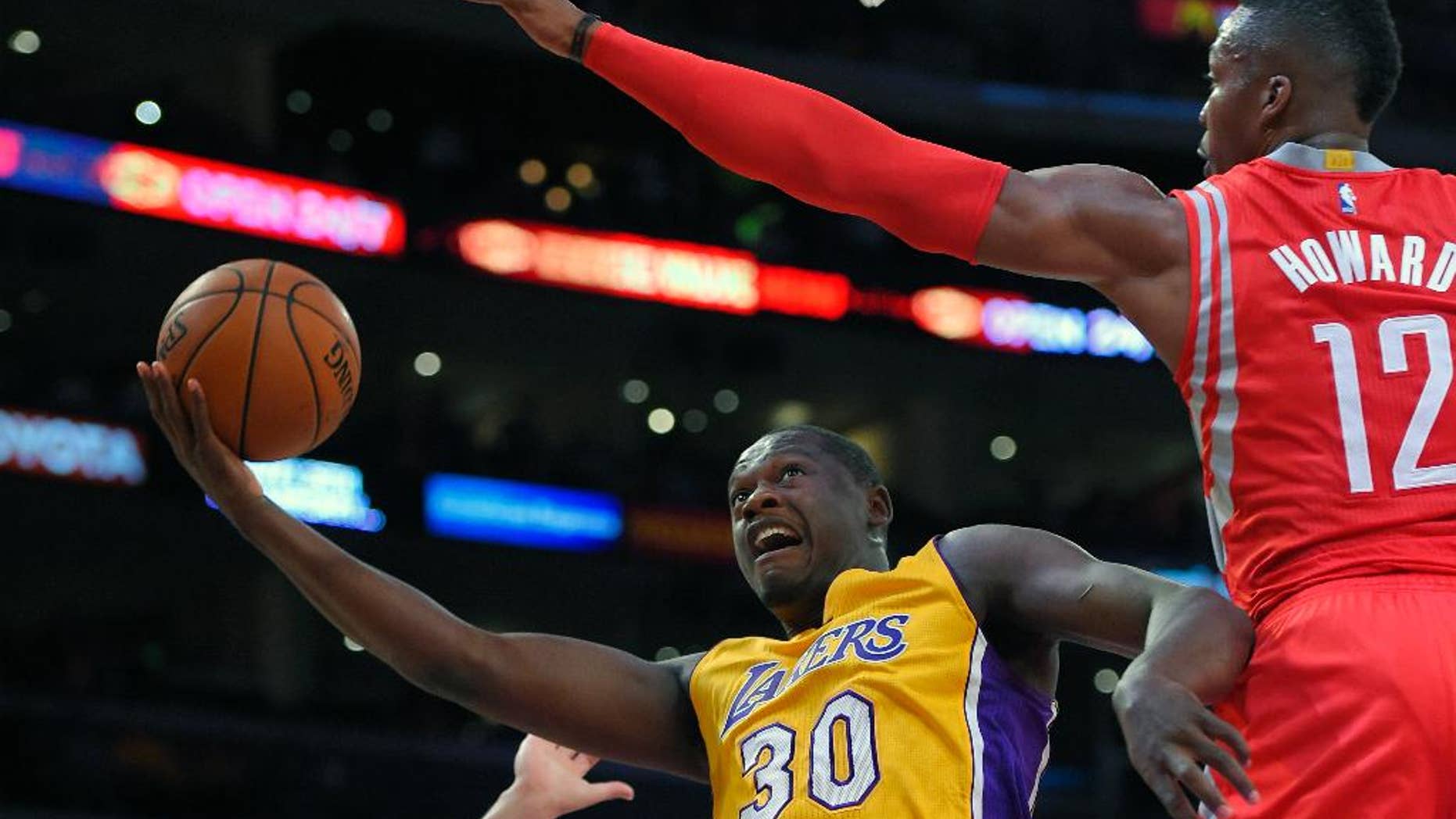 Los Angeles Lakers forward Julius Randle, left, puts up a shot as Houston Rockets center Dwight Howard defends during the first half of an NBA basketball game, Tuesday, Oct. 28, 2014, in Los Angeles. (AP Photo/Mark J. Terrill)