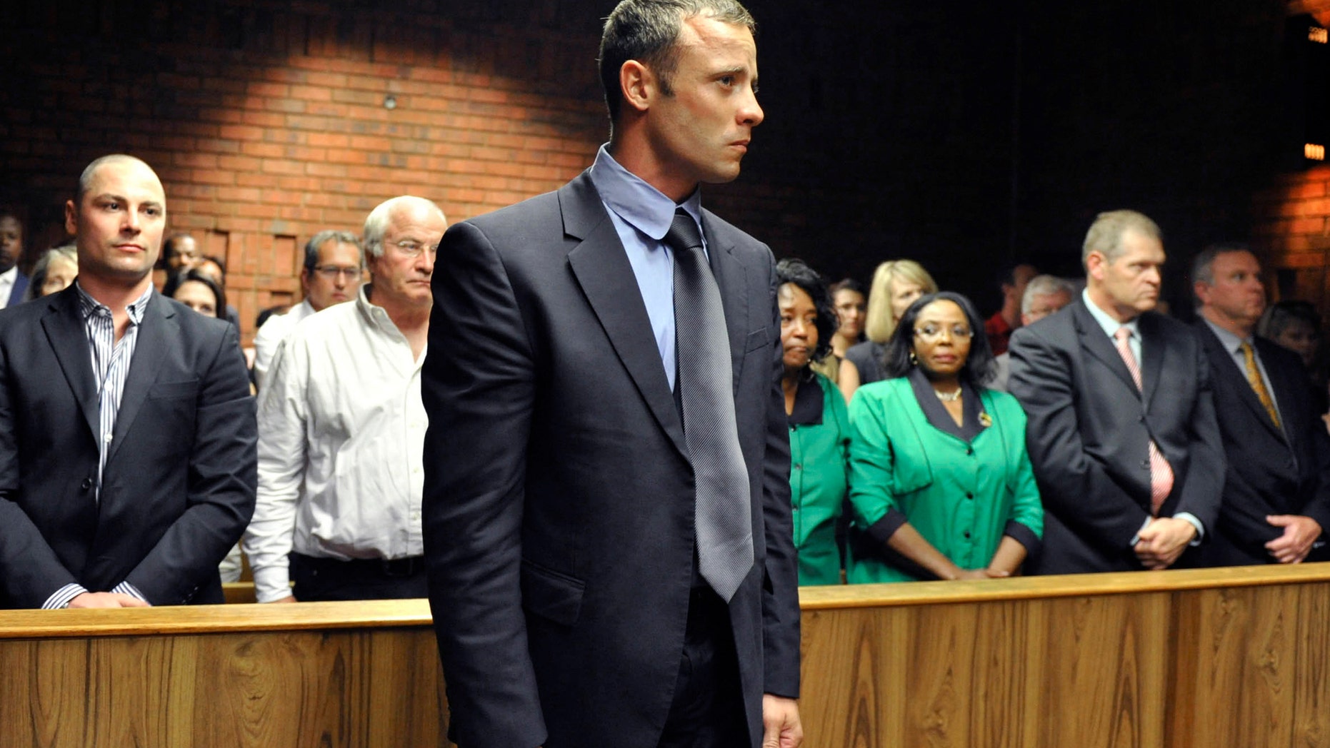 Olympian Oscar Pistorius stands following his bail hearing in Pretoria, South Africa, Tuesday, Feb. 19, 2013. Pistorius fired into the door of a small bathroom where his girlfriend was cowering after a shouting match on Valentine's Day, hitting her three times, a South African prosecutor said Tuesday as he charged the sports icon with premeditated murder. The magistrate ruled that Pistorius faces the harshest bail requirements available in South African law. He did not elaborate before a break was called in the session. (AP Photo)