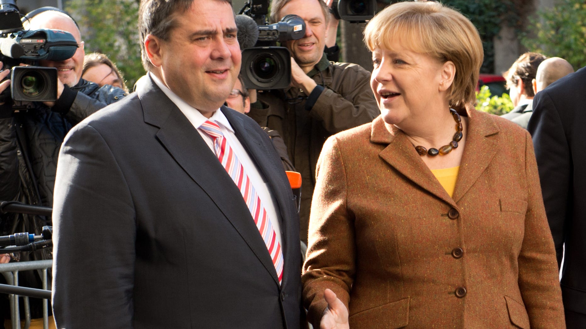 Social Democratic Party, SPD, chairman Sigmar Gabriel, left, welcomes Angela Merkel, right, German Chancellor and chairwoman of the Christian Democratic Union, CDU, center, at the Social Democrat's headquarters for coalition talks in Berlin, Wednesday, Oct. 30, 2013. Following the Sept. 22 national elections Chancellor Merkel and her Christian parties' bloc are negotiating the second week on forming a coalition with the Social Democratic Party. (AP Photo/dpa, Rainer Jensen)