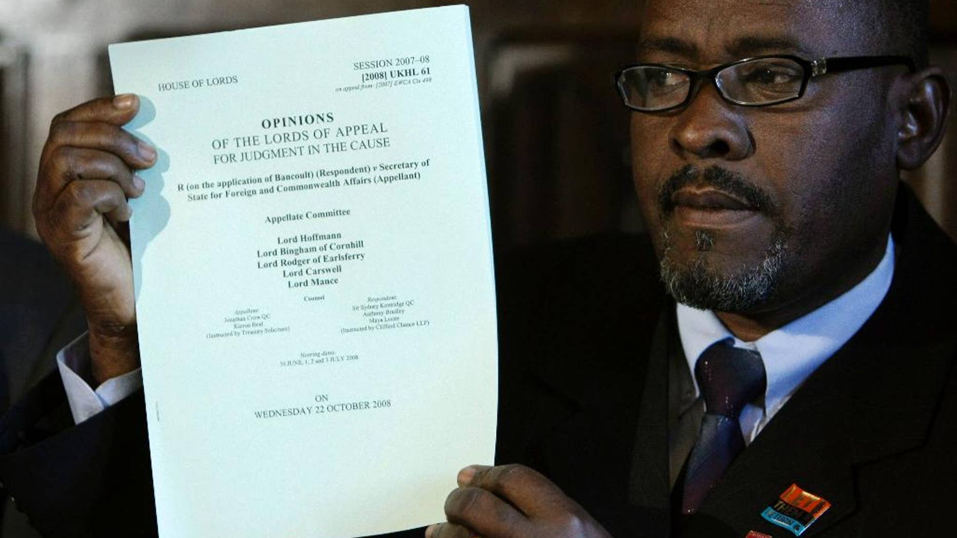 FILE - In this Wednesday, Oct. 22, 2008 file photo, Chagos Islander Olivier Bancoult holds up a judgment paper at the start of a news conference inside the Houses of Parliament in London, after a court ruling decided Chagos Islanders are not allowed to return to their homeland. Indian Ocean islanders who were forced from their homes decades ago to make way for a U.S. military base will not be allowed to return, the British government has announced. Britain evicted about 2,000 people from the tropical Chagos archipelago, a British colony, in the 1960s and 1970s so the U.S. military could build an air base on Diego Garcia, the largest of the islands. The British government announced Wednesday, Nov. 16, 2016 that it will continue to lease Diego Garcia to the U.S. until 2036. (AP Photo/Matt Dunham, File)