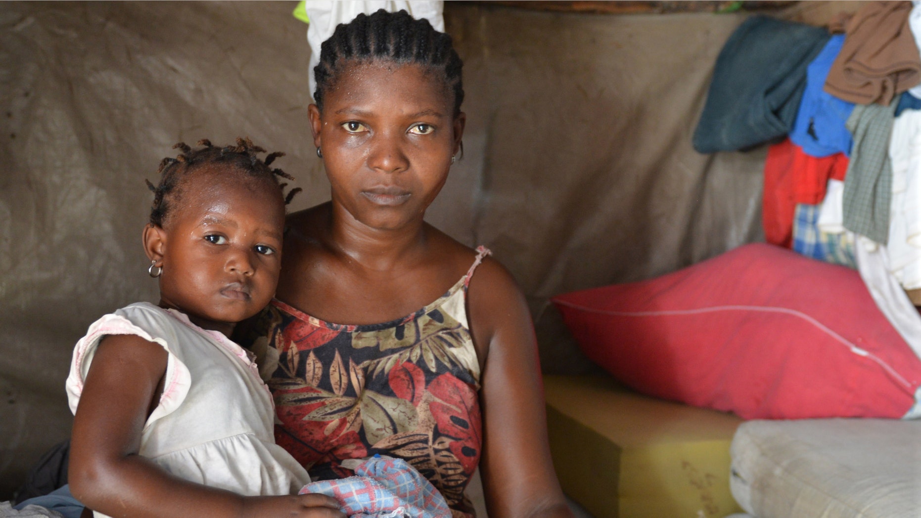 In this June, 30, 2014, photo, Delimene Saint Lise holds her 2-month-old daughter Gisline inside their tent home in the Delmas section of Port-au-Prince as the child suffers with a newly arrived mosquito-borne illness. Chikungunya virus has spread rapidly in Haiti, where the government has reported nearly tens of thousands of suspected cases since May. (AP Photo/David McFadden)