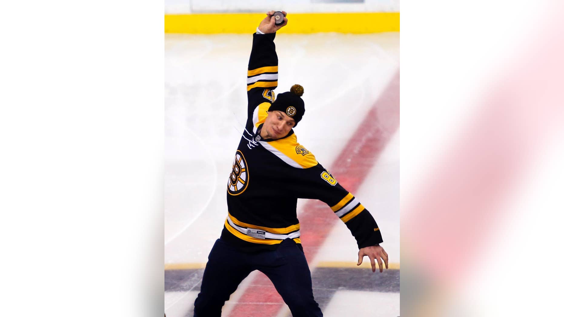 New England Patriots tight end Rob Gronkowski spikes a hockey puck at center ice before an NHL hockey game between the Boston Bruins and the New York Islanders in Boston Saturday, Feb. 7, 2015. (AP Photo/Winslow Townson)