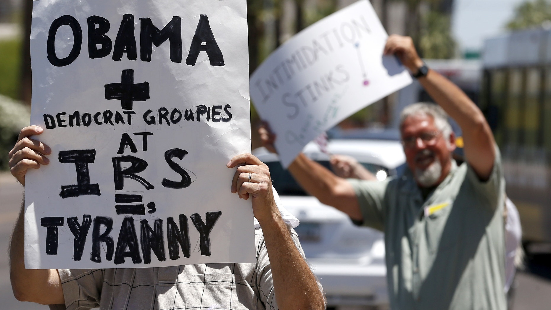Several dozen tea party activists and other concerned citizens, wave signs and small American flags as they march outside the main Internal Revenue Service office on Tuesday, May 21, 2013, in Phoenix. The rally was one of many around the country after IRS officials acknowledged that some conservative groups received inappropriate attention and questioning. (AP Photo/Ross D. Franklin)