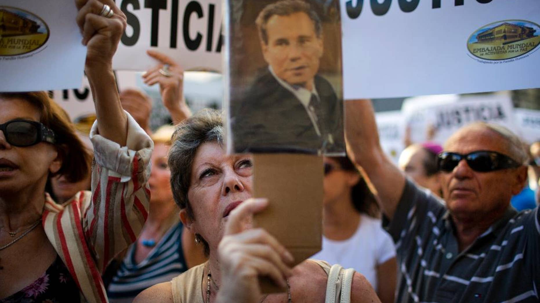 FILE - In this Jan. 21, 2015, file photo, a woman chants the Argentine national anthem holding a portrait of the late prosecutor Alberto Nisman outside the AMIA Jewish community center in Buenos Aires, Argentina. Nisman who accused the government of secret deals with Iran over the investigation was found shot dead at his apartment early Monday, Jan. 19, 2015. An Argentine prosecutor has dismissed the accusations made by Nisman against President Cristina Fernandez that she helped shield Iranian officials allegedly behind the 1994 bombing of a Jewish community center. (AP Photo/Rodrigo Abd, File)