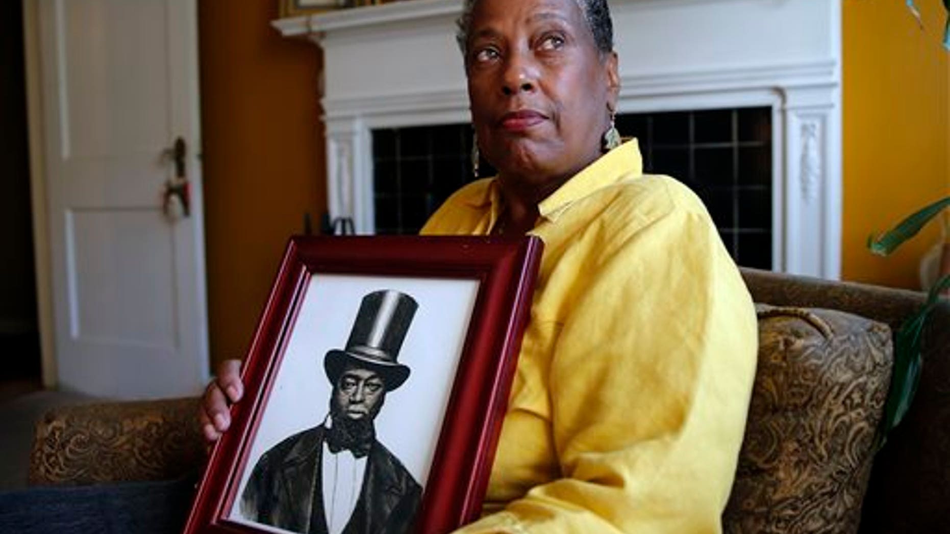 Ocea Thomas poses for a portrait with a picture of her ancestor Samuel Burris.