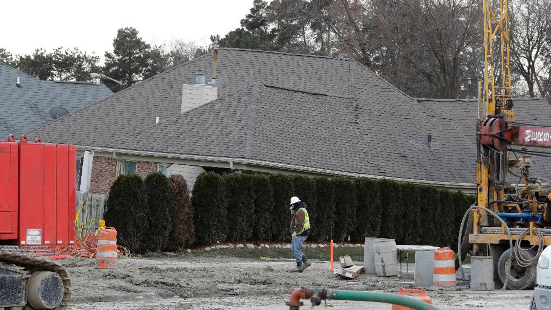FILE - In this Jan. 4, 2017 file photo, a construction worker walks by a home collapsed by a sinkhole in Fraser, Mich. Repairs to a broken sewer line that caused a massive sinkhole north of Detroit are estimated at more than $78 million. (AP Photo/Carlos Osorio)