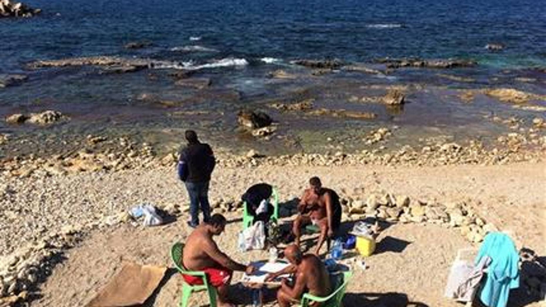 Lebanese men play cards and smoke water pipe, as they sunbath during unusually warm weather at the Mediterranean Sea off the Corniche, or waterfront promenade, in Beirut, Lebanon. Earth got so hot last month that federal scientists struggled to find words, describing temperatures as astronomical,staggering and strange. (AP Photo/Hussein Malla)