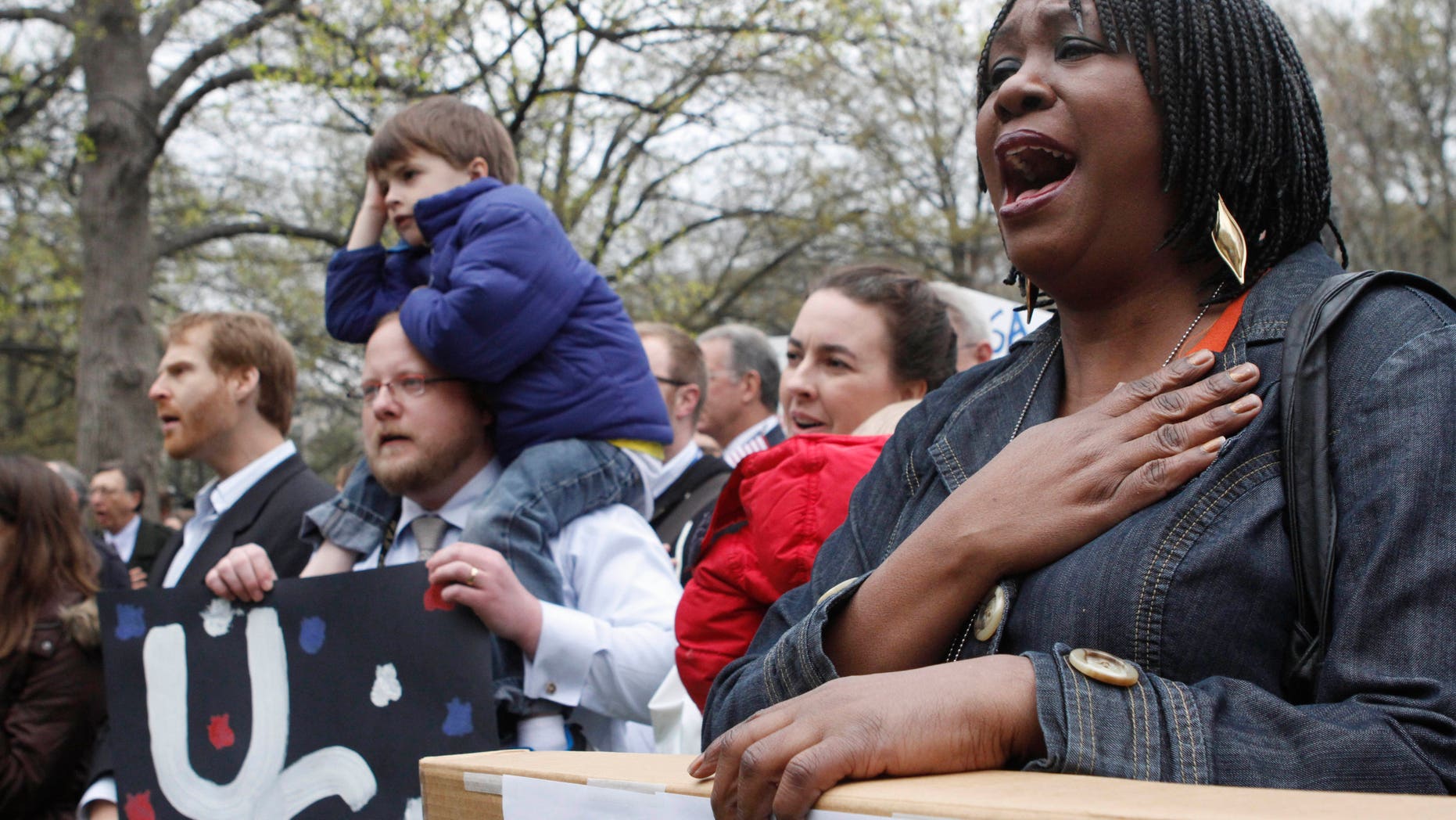 Esther Mayberry, with the State Department, right, sings "America the Beautiful" during a rally of U.S. diplomats and federal workers against the prospect of a government shutdown, Friday, April 8, 2011, in Washington. (AP)