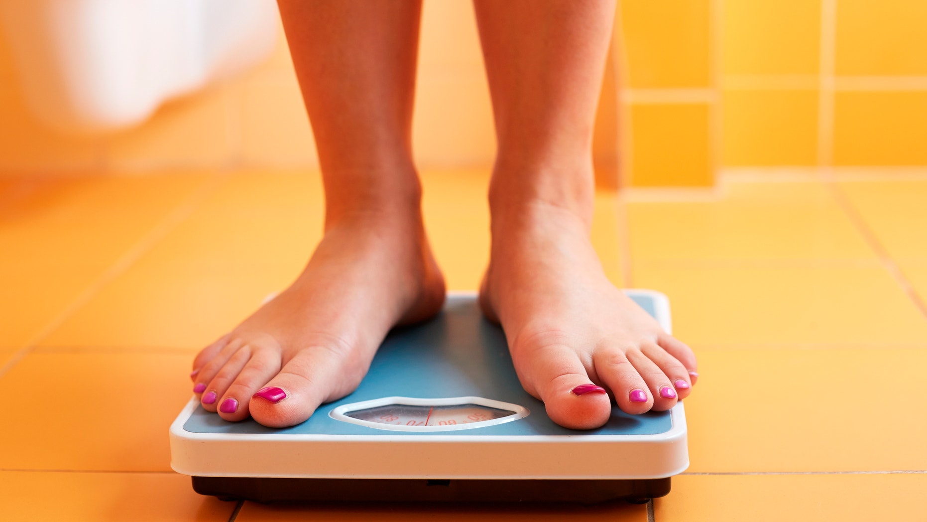 A pair of female feet standing on a bathroom scale