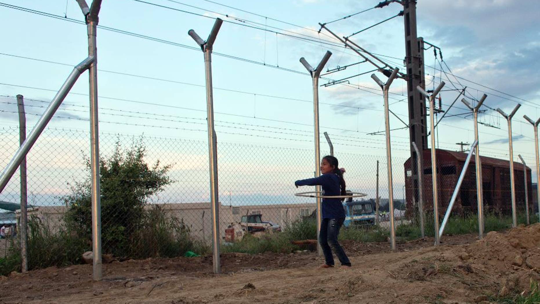 A girl plays next to the fence on the Macedonian border in Idomeni, Greece, Thursday, May 19, 2016. Thousands of stranded refugees and migrants have camped in Idomeni for months after the border was closed. (AP Photo/Darko Bandic)