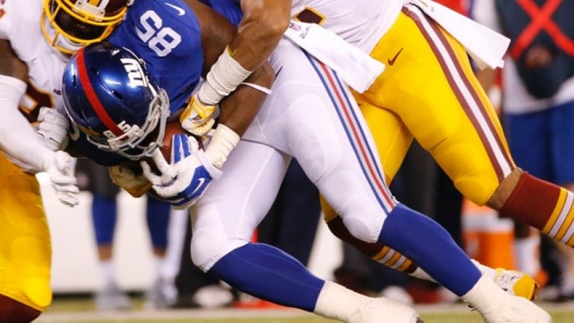 Washington Redskins strong safety Trenton Robinson and Keenan Robinson tackle New York Giants tight end Daniel Fells. (AP)
