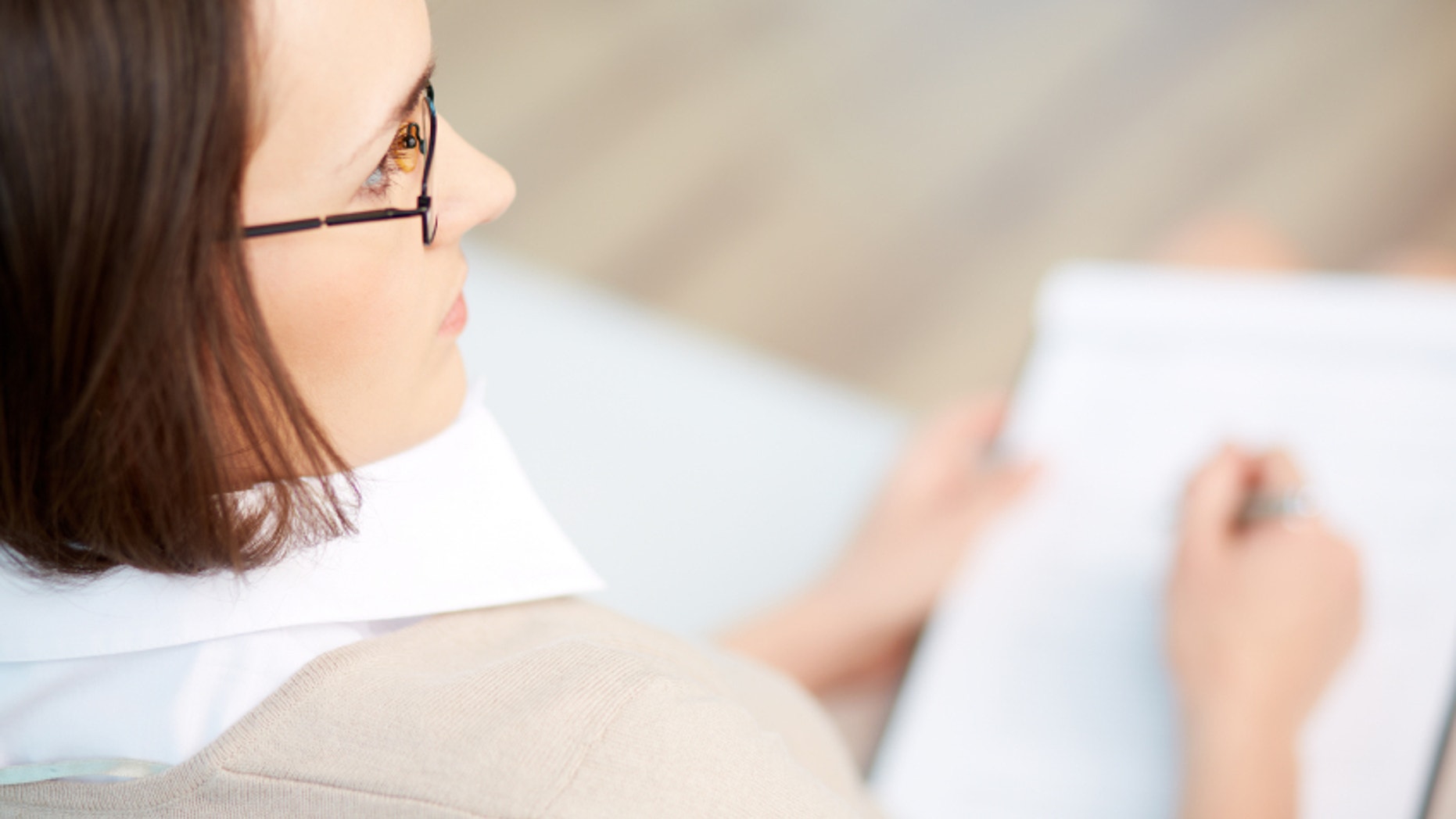Professional psychiatrist keeping record during therapy session