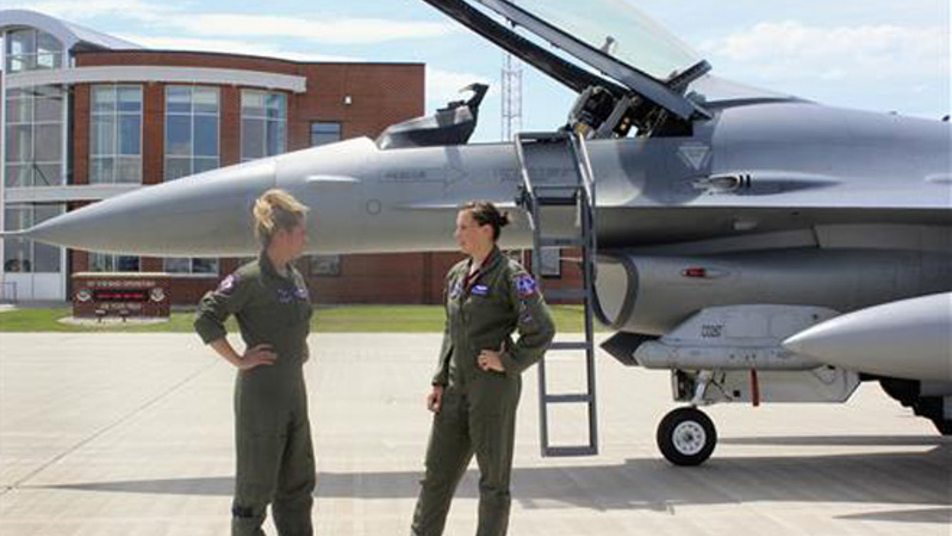 In this Tuesday, July 19, 2016, photo, Capt. Valerie Vanderostyne, left, and Capt. Shanon Davis, both with the South Dakota Air National Guard, chat alongside an F-16 Fighting Falcon at Joe Foss Field in Sioux Falls, S.D.