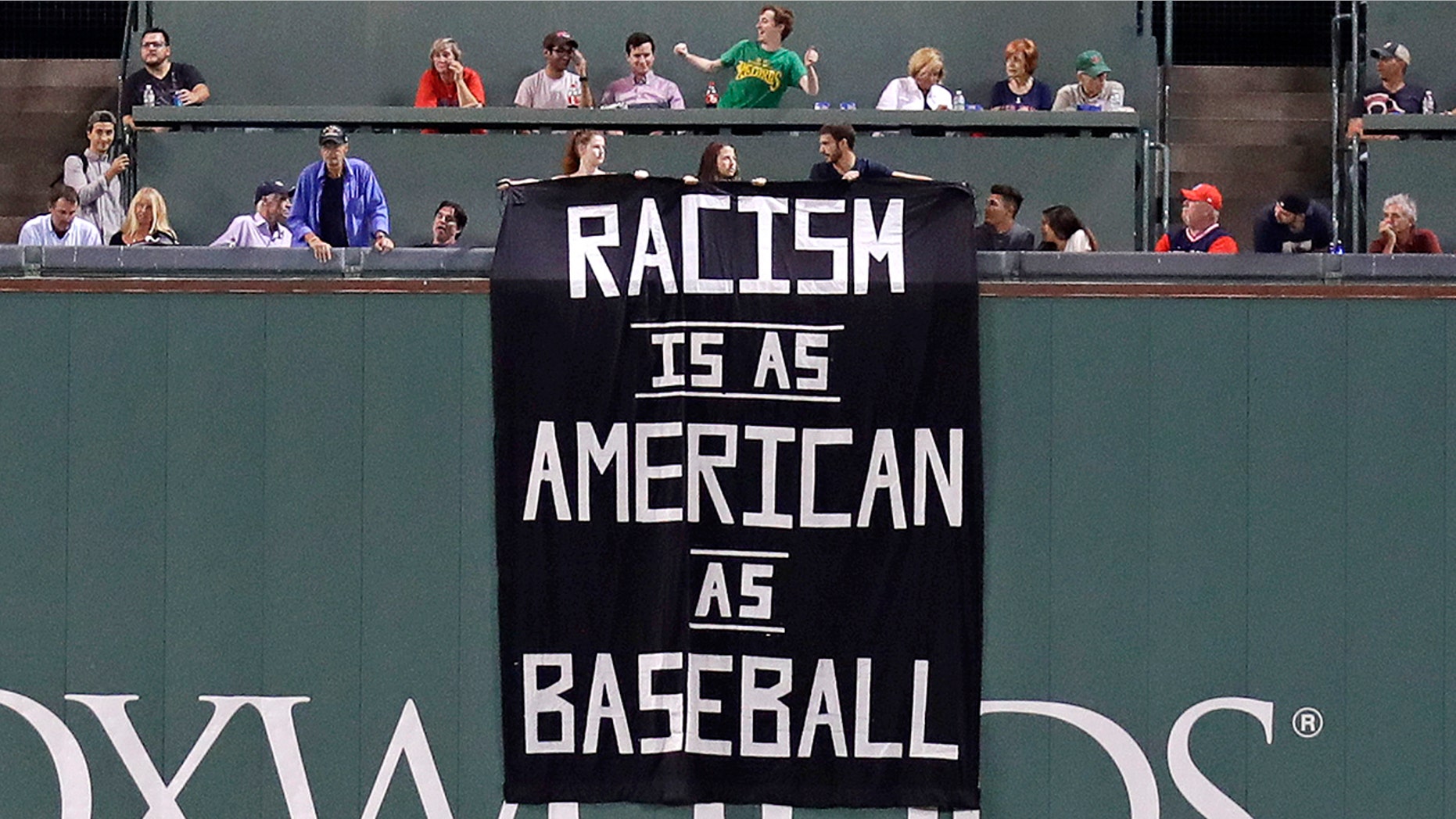 A banner is unfurled over the left field wall at Fenway Park in Boston Wednesday night.