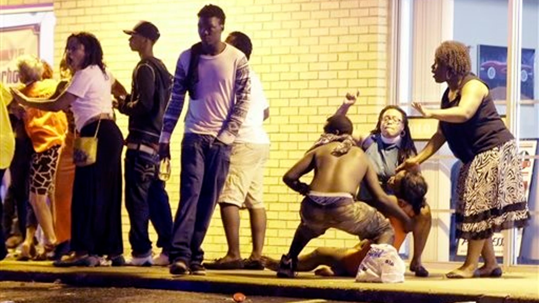 People come to the aid of a distraught woman after gunshots were fired near a protest in Ferguson, Mo., Sunday, Aug. 9, 2015. The one-year anniversary of Michael Brown's death in Ferguson began with a march in his honor and ended with a protest that was interrupted by gunfire. (AP Photo/Jeff Roberson)