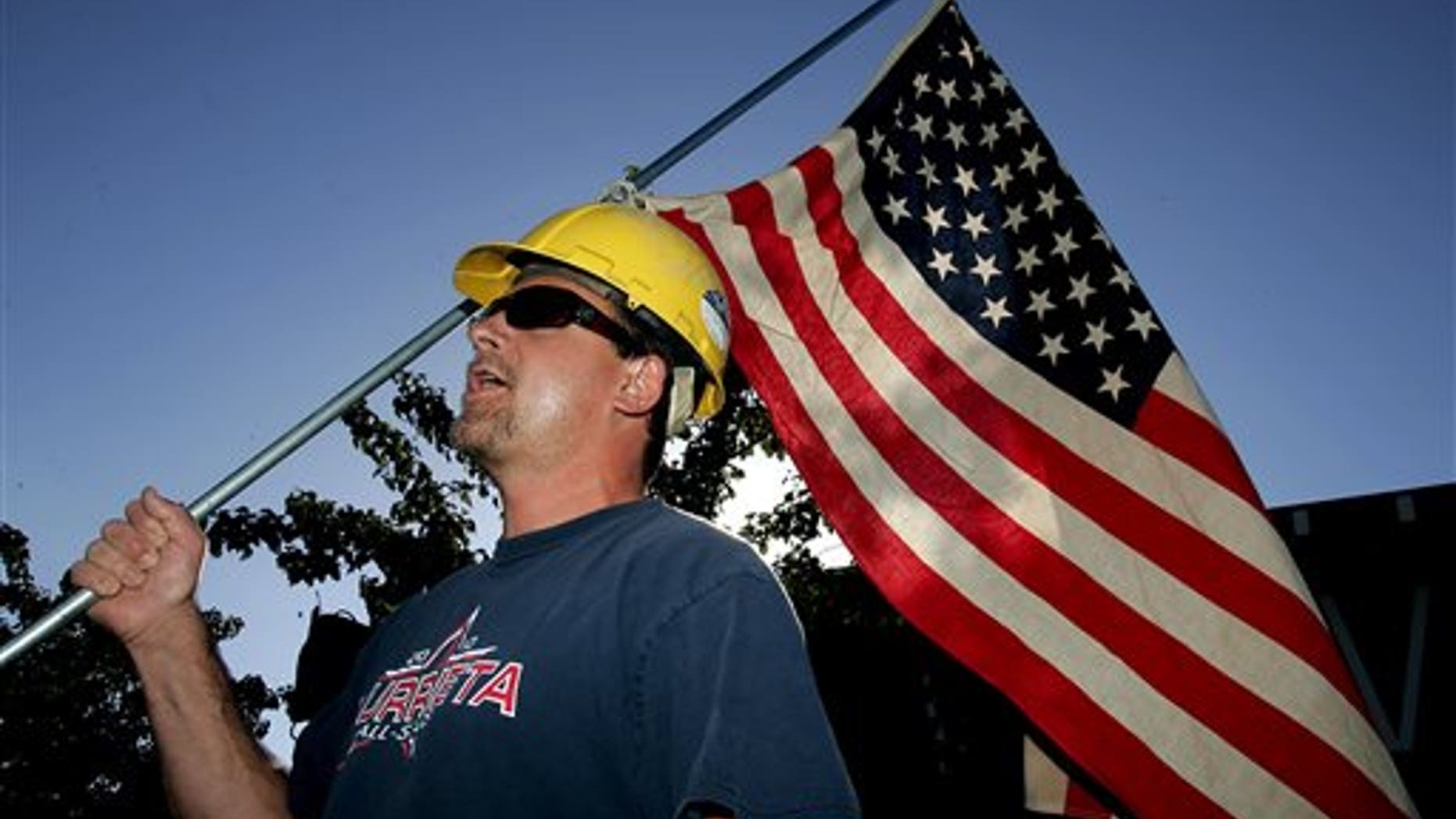 Paul Hathaway, of Murrieta, Calif., holds a U.S. flag as he shouts outside Murrieta Mesa High School in Murrieta, Calif., where city, Riverside County and federal officials spoke about a plan to process immigrants detained in Texas at the Murrieta U.S. Border Patrol facility, Wednesday, July 2, 2014. (AP Photo/The Press-Enterprise, Terry Pierson)