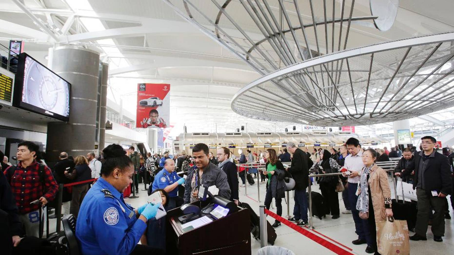 FILE - In this Oct. 30, 2014, file photo, a TSA officer, left, checks a passenger's ticket, boarding pass and passport as part of security screening at John F. Kennedy International Airport in New York. A court challenge over the difficulty for airline passengers to remove their names from the U.S. government’s no-fly list is taking an unexpected twist, now focusing on the mysterious ways federal agents add passenger names to the list in the first place. (AP Photo/Mark Lennihan, File)