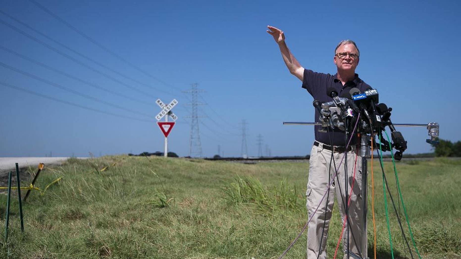National Transportation Safety Board (NTSB) member Robert Sumwalt talks about power lines, left, during a news conference at the scene of Saturday's hot air balloon crash near Lockhart, Texas, Monday, Aug. 1, 2016. The balloon made contact with the wires. Sixteen people were killed in the crash. (Deborah Cannon/Austin American-Statesman via AP)