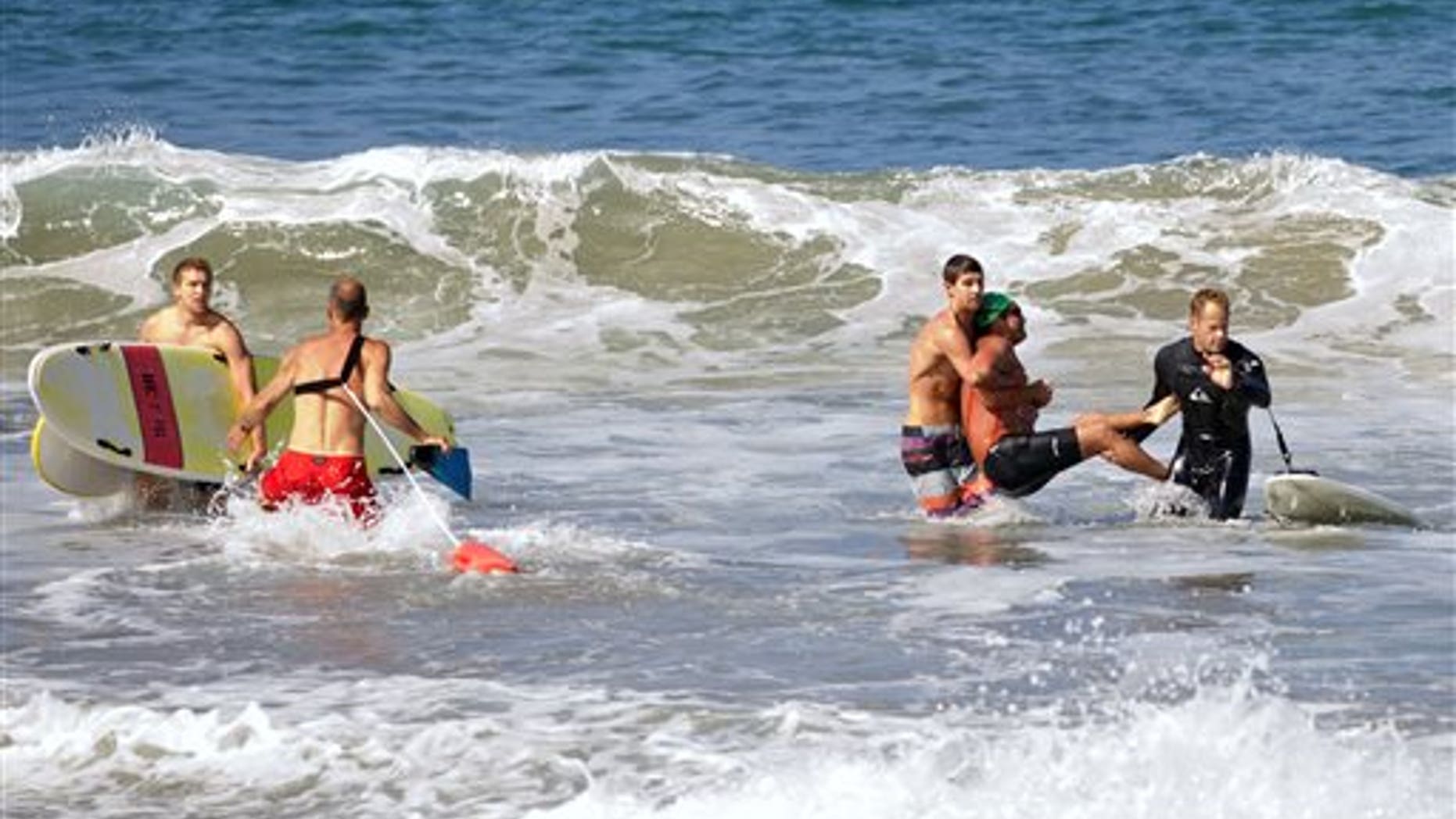 In this photo by Laura Joyce of goofyfootphotography.com, two men carry a swimmer, second from right, after he was bitten by a great white shark, as lifeguards close in at left in the ocean off Southern Californias Manhattan Beach, Saturday, July 5, 2014. The man, who was with a group of long-distance swimmers when he swam into a fishing line, was bitten on a side of his rib cage according to Rick Flores, a Los Angeles County Fire Department spokesman. The mans injuries were not life-threatening and he was taken to a hospital conscious and breathing on his own, Flores said. (AP Photo/goofyfootphotography.com, Laura Joyce)