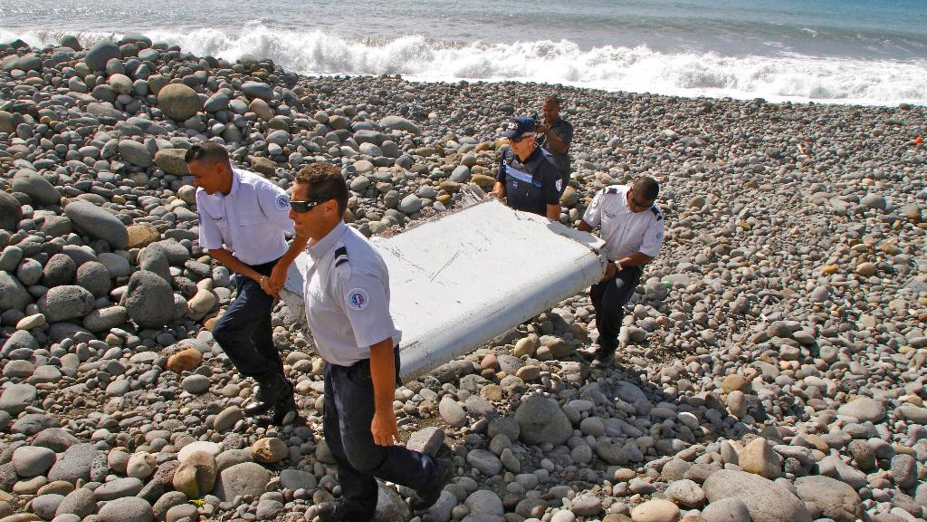 FILE - In this July 29, 2015, file photo, French police officers carry a piece of debris from a plane known as a flaperon in Saint-Andre, Reunion Island. The barnacle-encrusted part was the first trace of Malaysia Airlines Flight 370 that disappeared two years ago. Malaysia's confirmation on Thursday, May 12, 2016, that other debris found in March 2016 came from missing Malaysia Airlines Flight 370 brings to five the number of parts that have been recovered from the aircraft that vanished two years ago. (AP Photo/Lucas Marie, File)