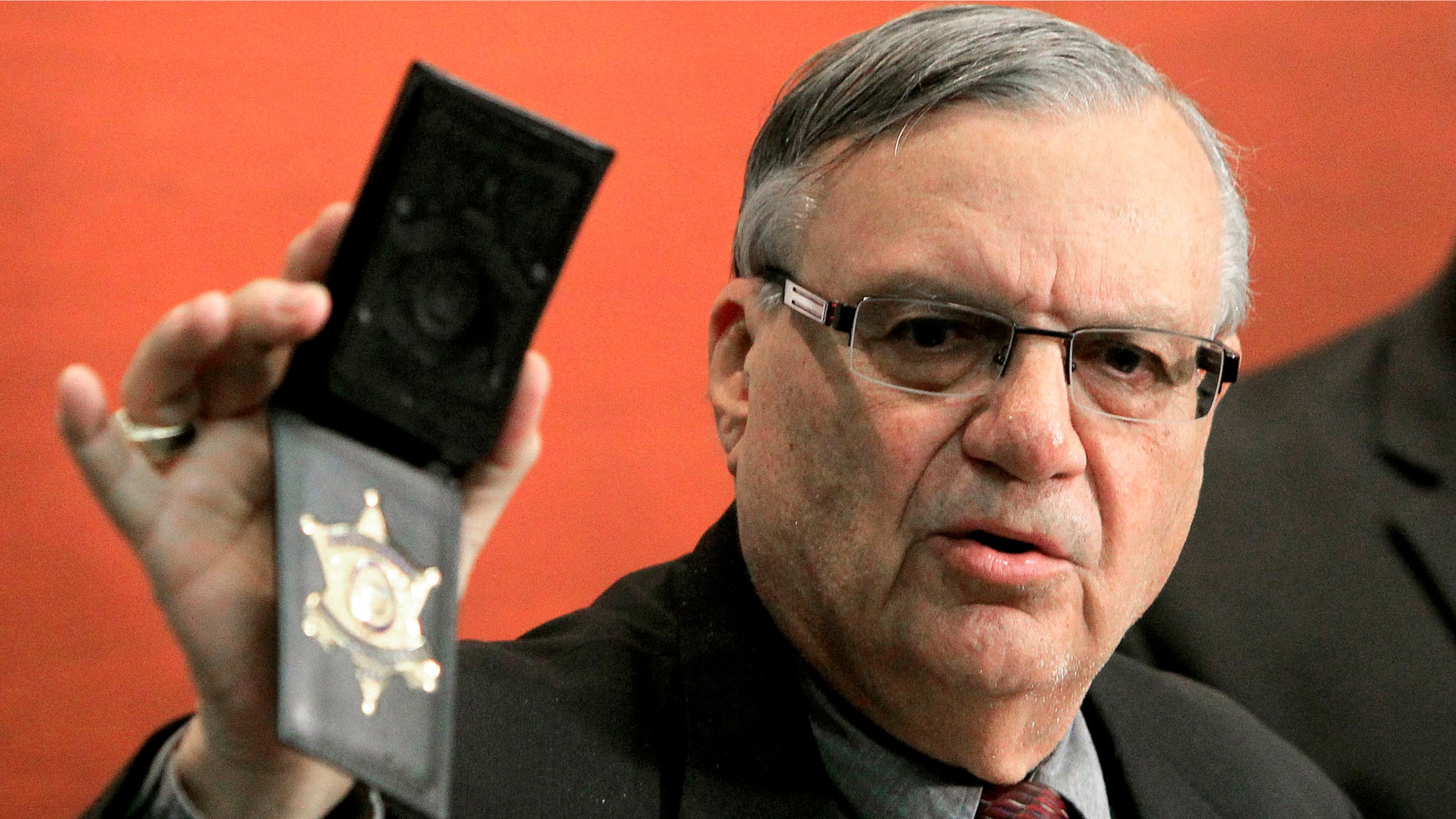 Maricopa County Sheriff Joe Arpaio shows his badge as he holds a ceremony where 92 of his immigration jail officers, who lost their federal power to check whether inmates are in the county illegally, turn in their credentials after federal officials pulled the Sheriff's office immigration enforcement powers Wednesday, Dec. 21, 2011, in Phoenix. The U.S. Department of Homeland Security stripped Sheriff Joe Arpaio's jail officers of their federal powers after federal authorities accused the sheriff's office last week of a wide range of civil rights violations. (AP Photo/Ross D. Franklin)