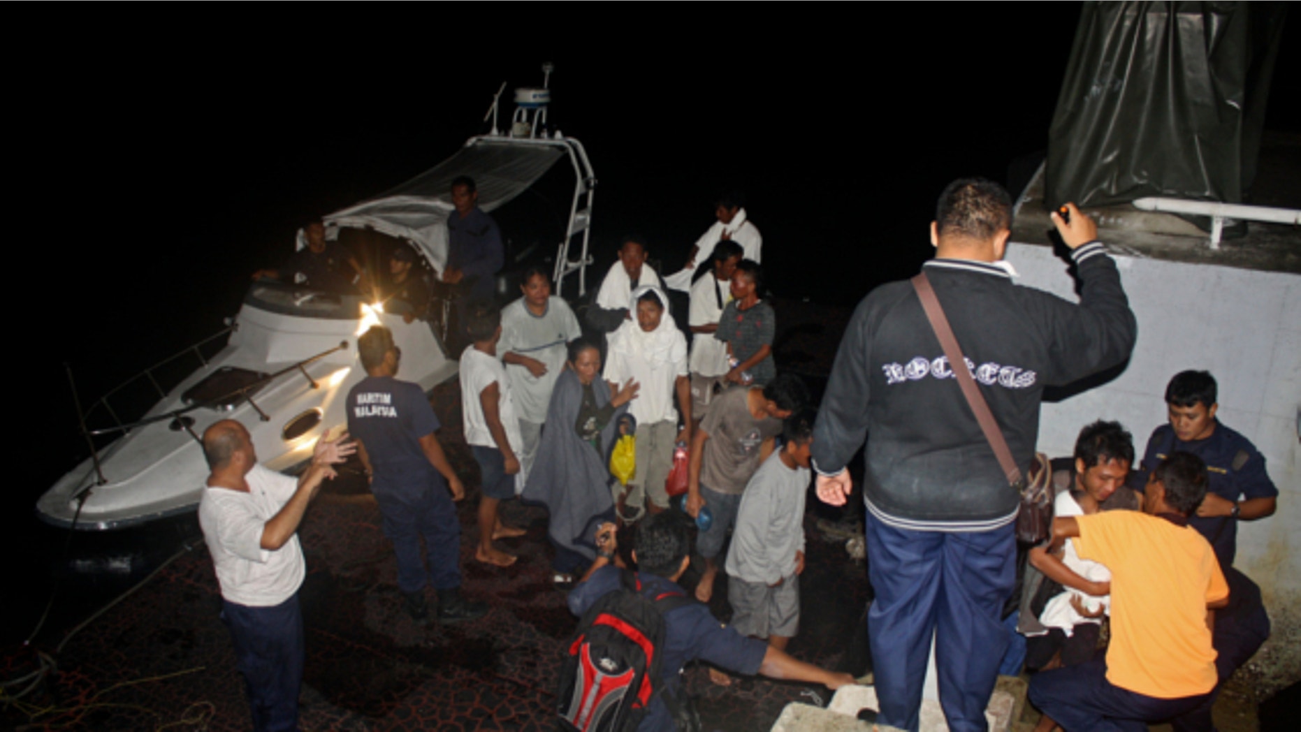 FILE: July 18, 2013: This photo released by Malaysian Maritime Enforcement Agency shows Indonesian passengers who were rescued from an overturned boat at a jetty in Tanjung Sedili, Johor state, Malaysia.