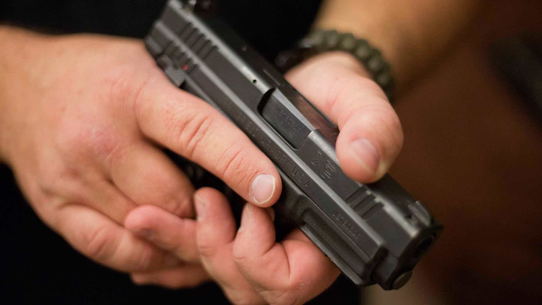 Phil Burns, a firearms instructor, holds a handgun that he carries as part of his survival supplies at his home in American Fork, Utah, Dec. 14, 2012. (REUTERS/Jim Urquhart)