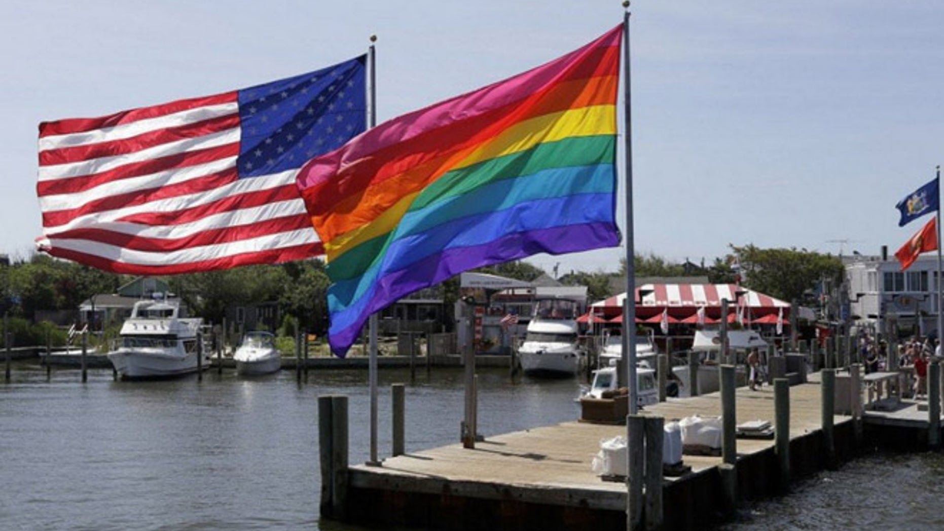 An American flag and a gay pride banner wave together on Fire Island, a barrier island off New York that is a popular summer destination for LGBT revelers. (AP)