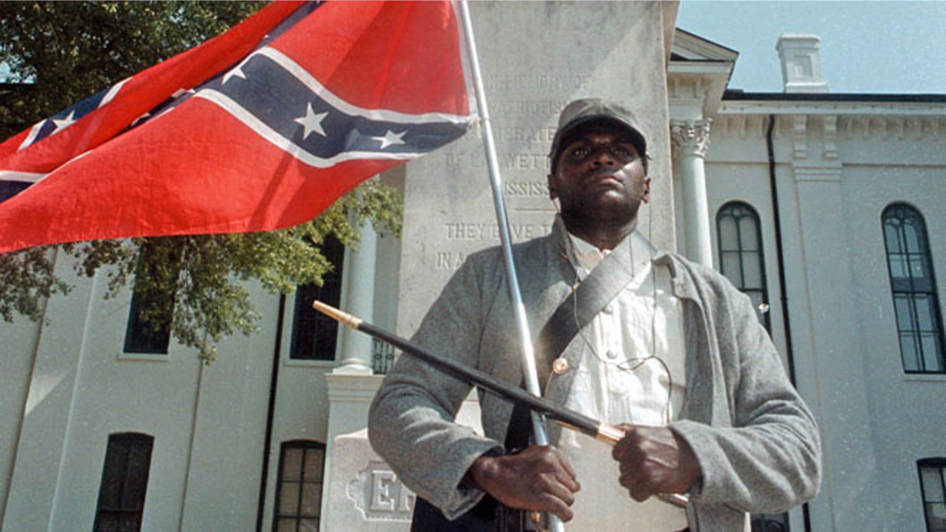 Anthony Hervey holds a Confederate flag while standing underneath the Confederate monument in Oxford, Miss in 2000.