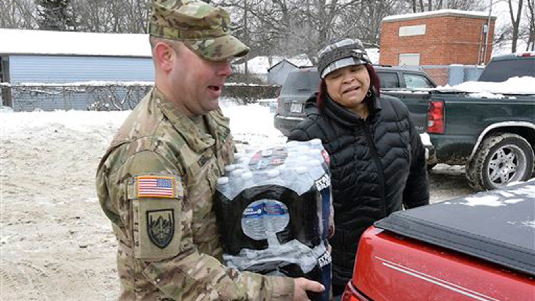 Michigan Sgt. Steve Kiger, left, carries cases of water for a Flint resident, Wednesday Jan 13, 2016 in Flint, Mich. (Dale G. Young/Detroit News via AP)
