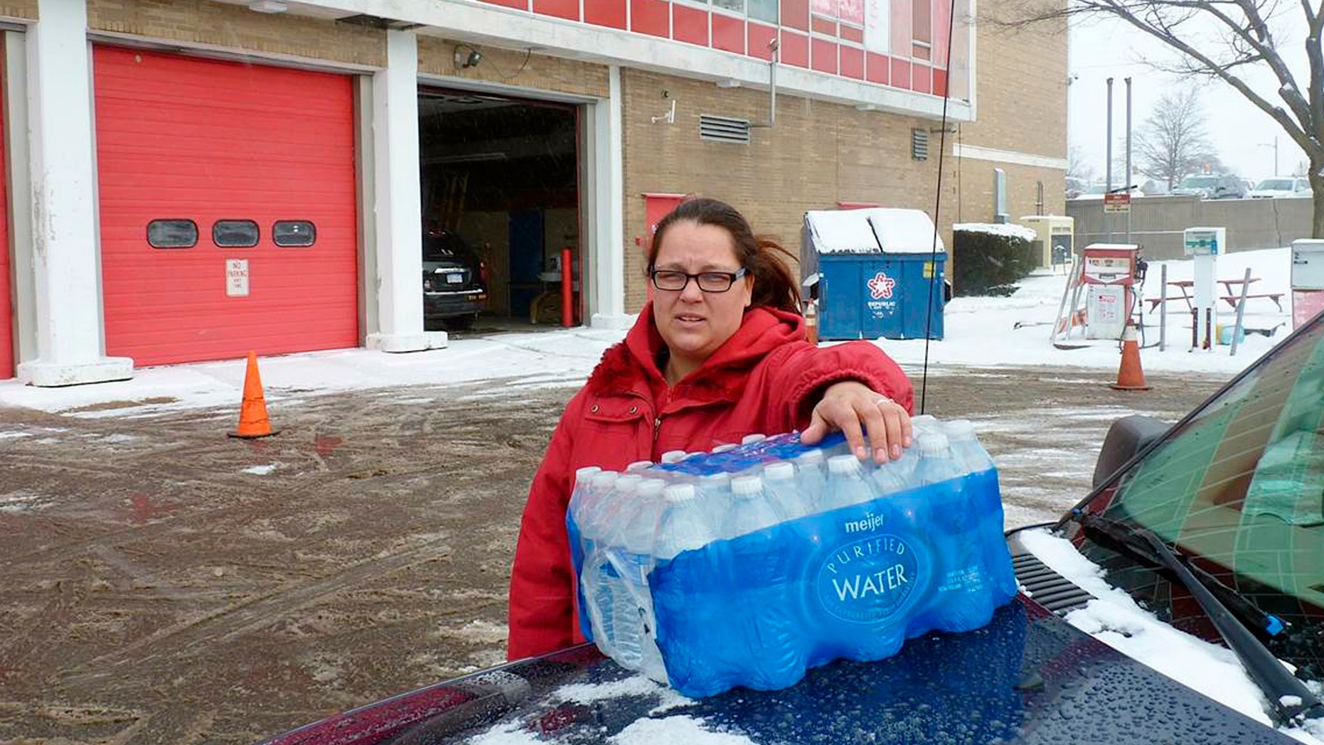 Rabecka Cordell picks up a case of bottled water outside the fire station in Flint, Mich.