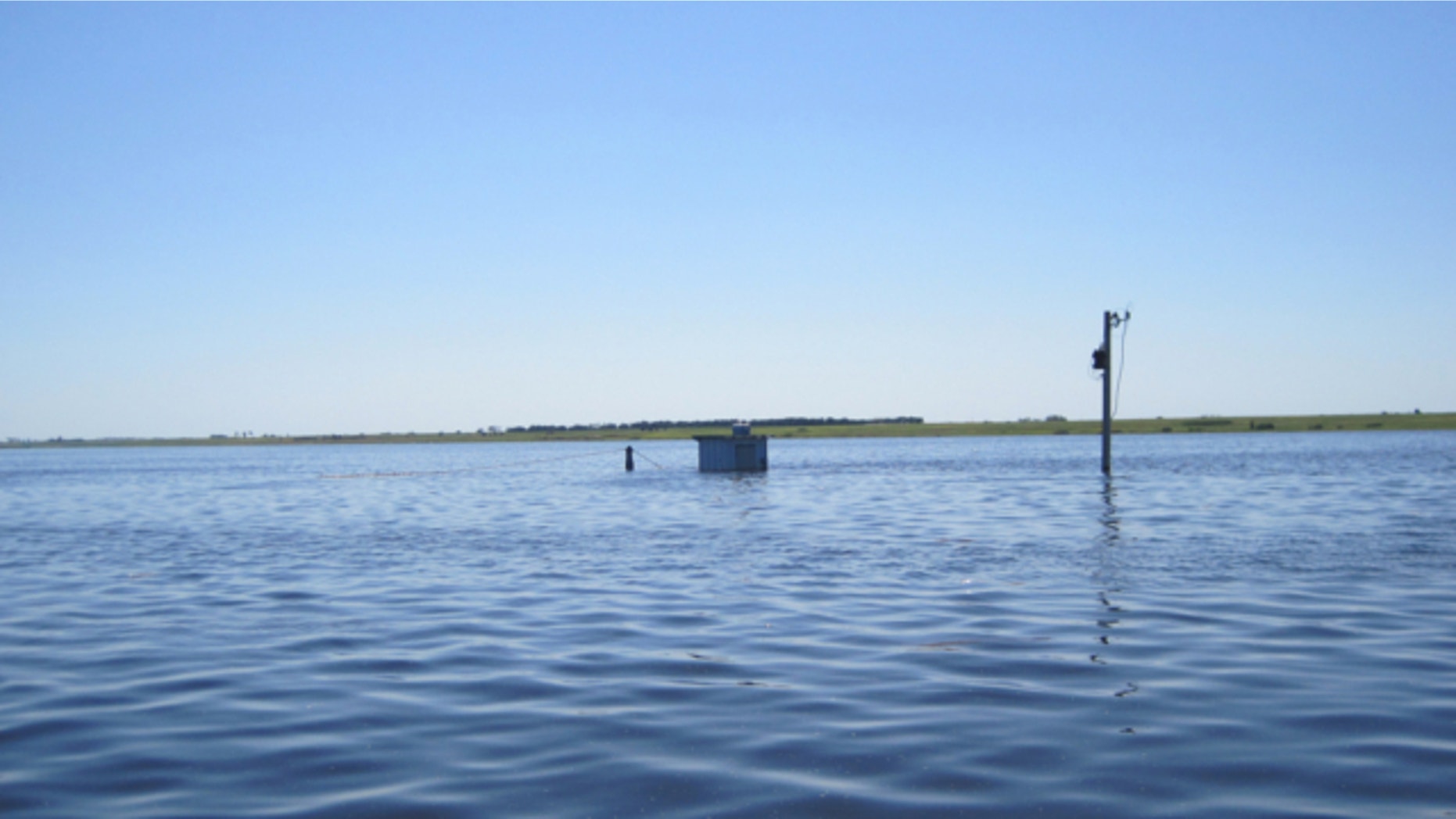 July 5, 2011: This handout photo provided by the US Geological Survery (USGS), taken near Westhope, N.D., shows the Souris River at the peak for the great Souris River flood of 2011, with equipment stored in cooler bolted to roof of gage house because water level was above gage house shelf.