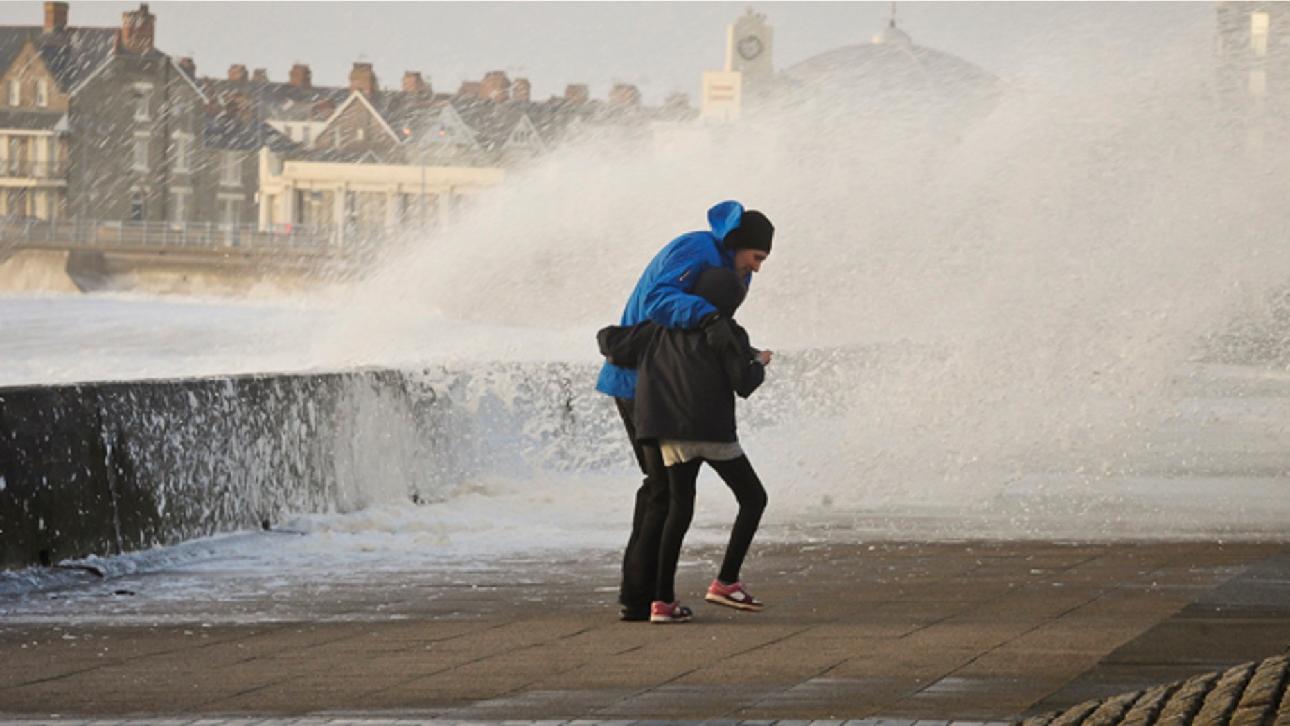 People struggle to make their way along the Esplanade, Porthcawl, south Wales, as the region continues to be battered by high winds and heavy rain.