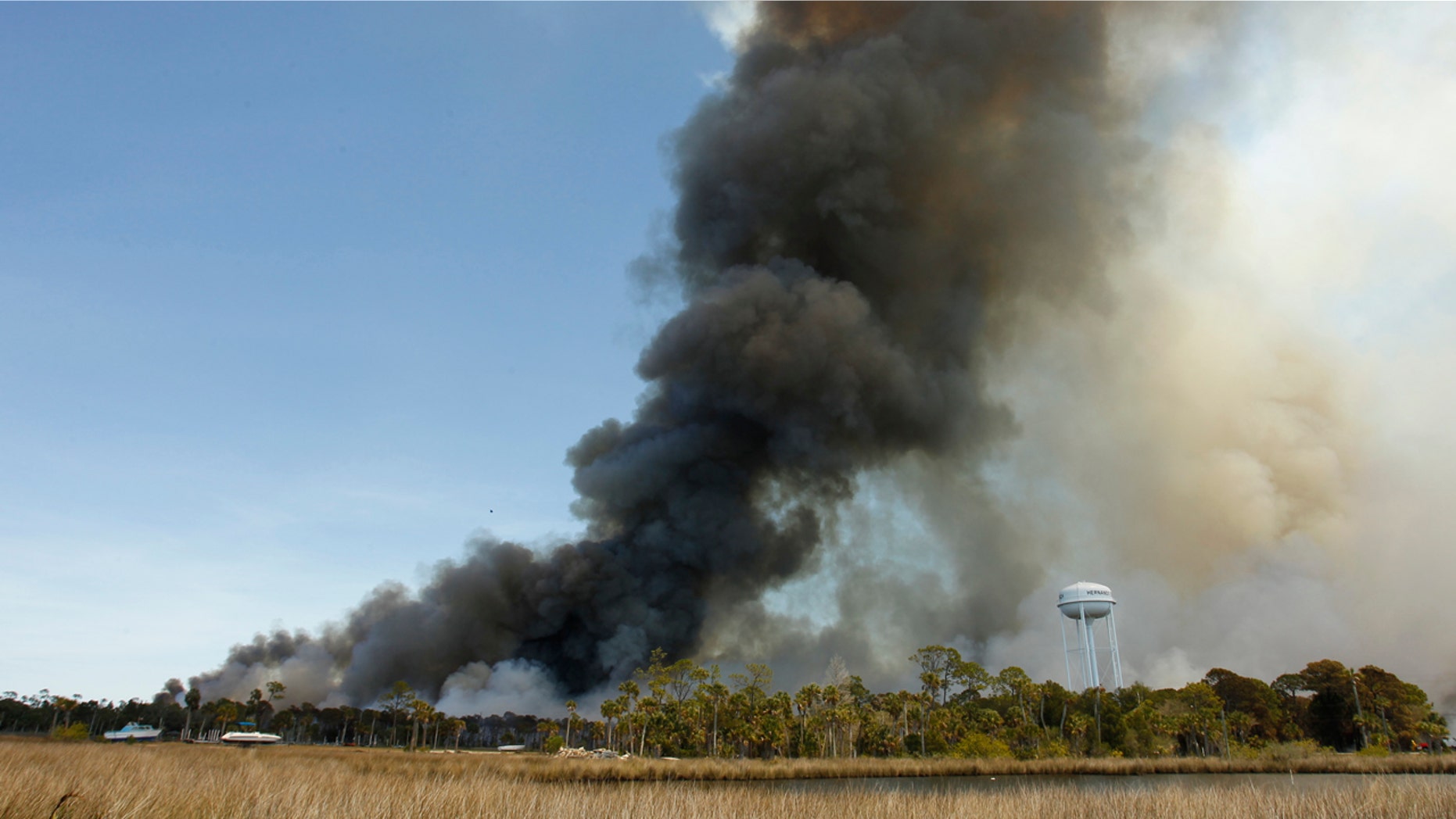 In this Saturday, April 8, 2017 photo, aircraft from the U.S. Forestry Service and the Florida Forestry Service work to contain a massive wildfire in Hernando Beach, Fla