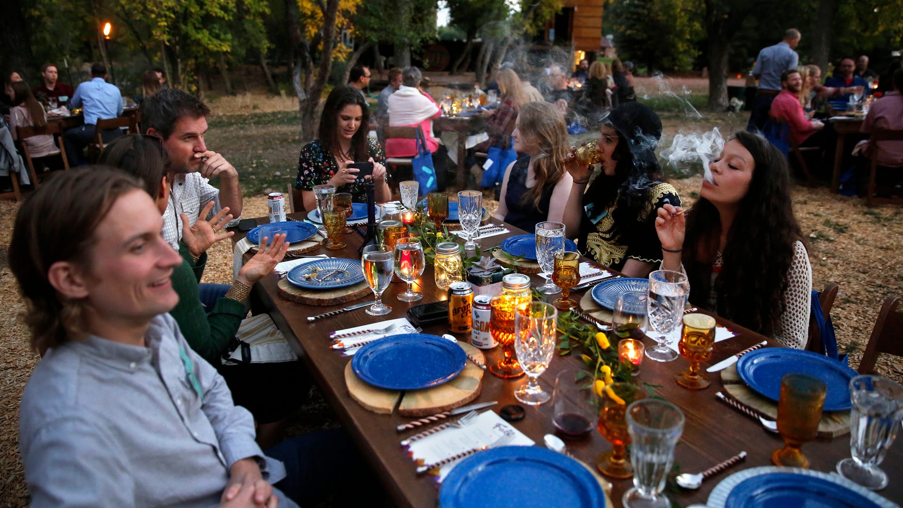 In this Oct. 2, 2016 photo, diners smoke marijuana as they eat dishes prepared by chefs during an evening of pairings of fine food and craft marijuana strains served to invited guests dining at Planet Bluegrass, an outdoor venue in Lyons, Colo.