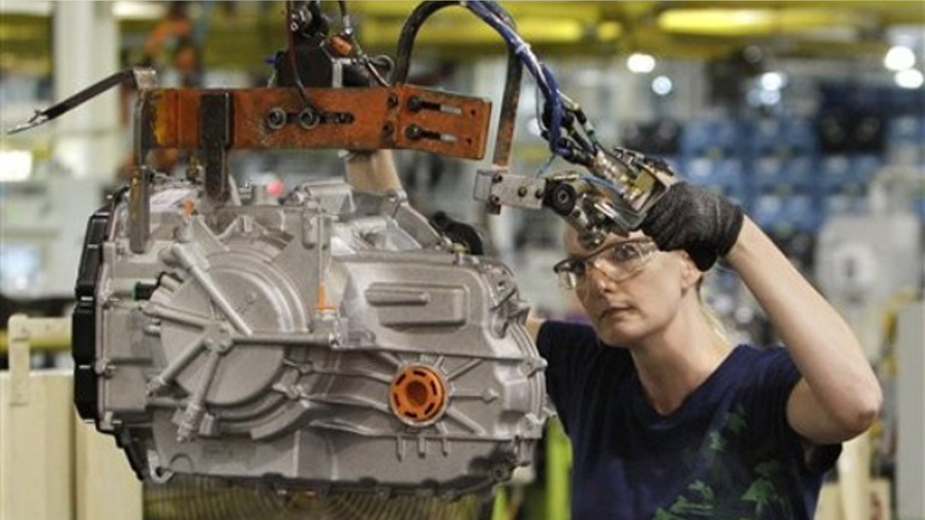 In this June 9 file photo, a line worker moves a transmission from the assembly line to a pallet at the Ford Van Dyke Transmission Plant in Sterling Heights, Mich.