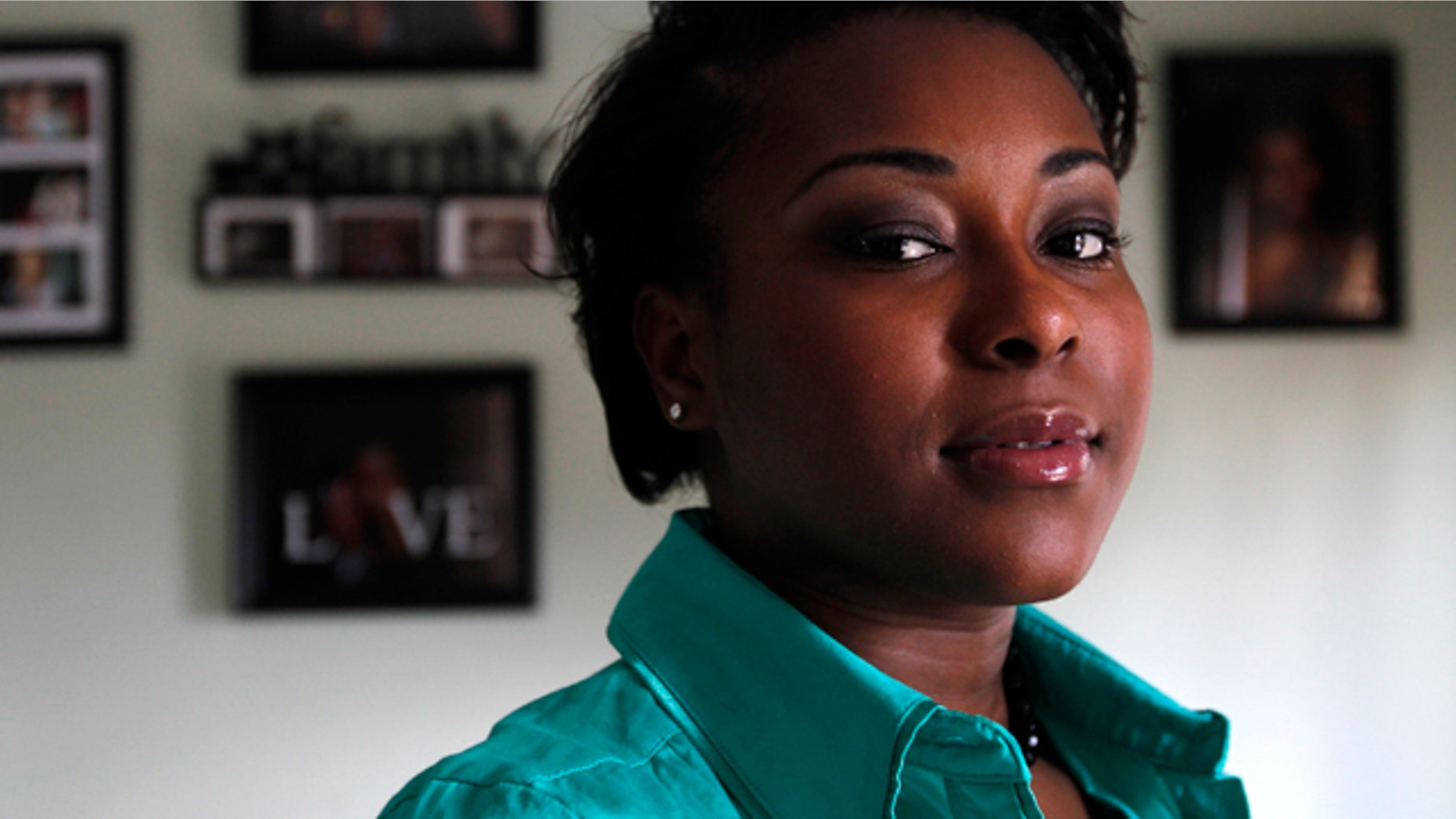 Oct. 5: Dee Saint Franc, 21, of Providence, R.I., stands for a portrait in front of family photos in her home. Saint Franc left the Rhode Island foster care system at age 18 eager to start life on her own. She went to a Verizon store to buy a phone and instead learned that someone had used her identity to rack up $3,000 worth of delinquent bills at Verizon dating back to 1998.