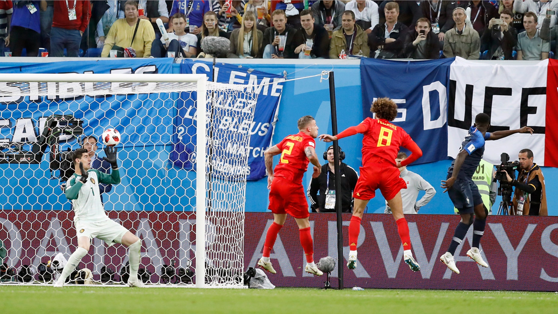 Samuel Umtiti, in blue, scores the only goal of the game bast Belgium's Thibault Courtois.