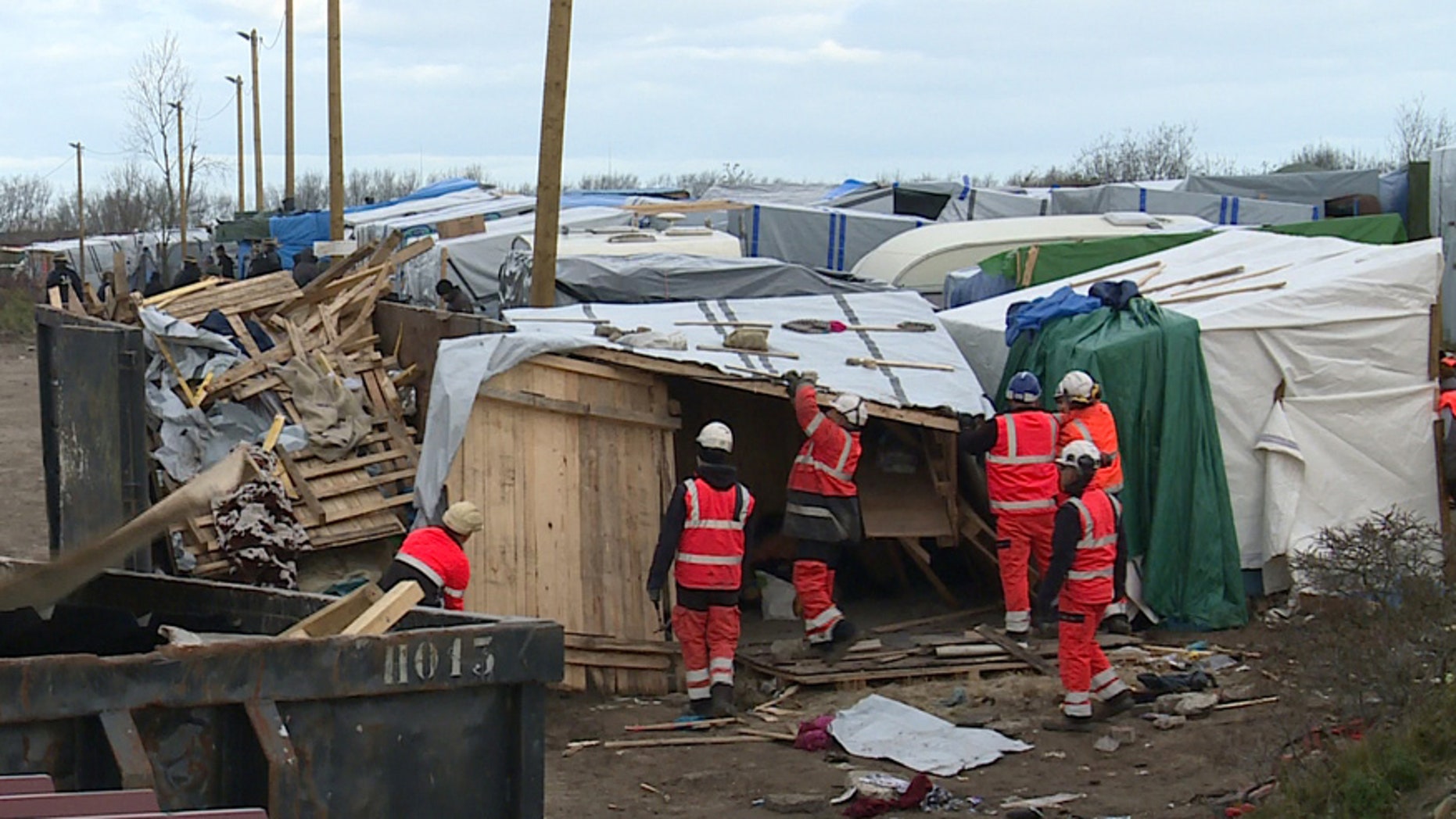 Feb. 29, 2016: Helmeted workers pull down makeshift structures where migrants sleep in the southern sector of the camp near the northern port of Calais, France.