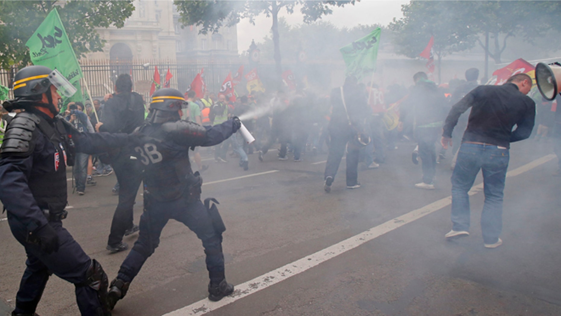 June 17, 2014: French riot police fire tear gas at striking train workers during a protest over a bill to reform the state-run railway system in Paris. A weeklong strike by rail workers has caused one of the worst disruptions to the countrys rail network in years and is heating up as the reform bill goes to the lower house of Parliament for debate Tuesday. France's Foreign ministry is in the background.