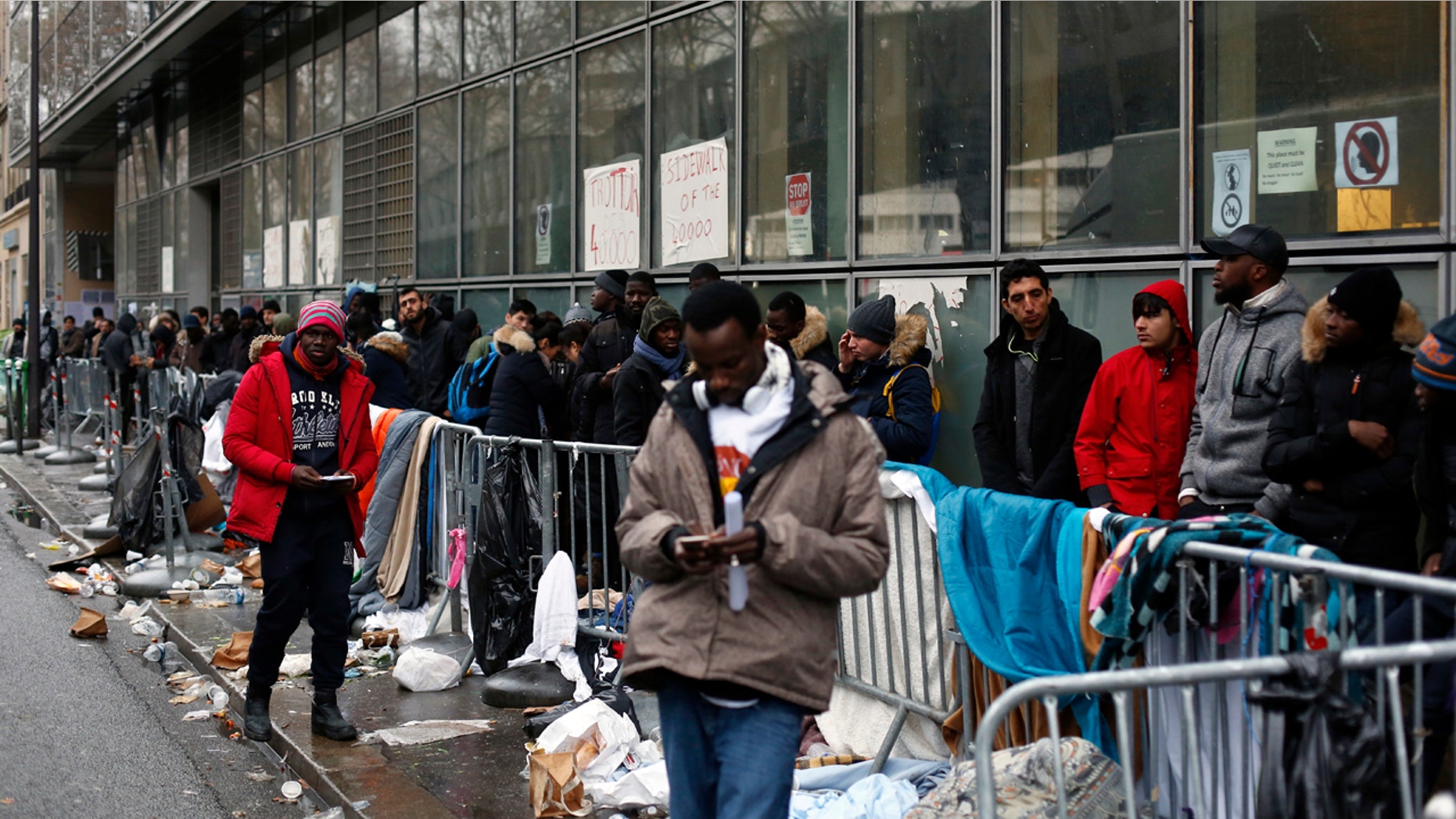 FILE - In this Dec.21, 2017 file photo, migrants queue outside a facility to apply for asylum, in Paris. French President Emmanuel Macron's government presents its first big immigration bill at Cabinet meeting Wednesday Feb.21, 2018. The government says the bill aims at accelerating expulsion of people who don't qualify for asylum and offering better conditions for those who are allowed to stay in the country. (AP Photo/Thibault Camus, File)