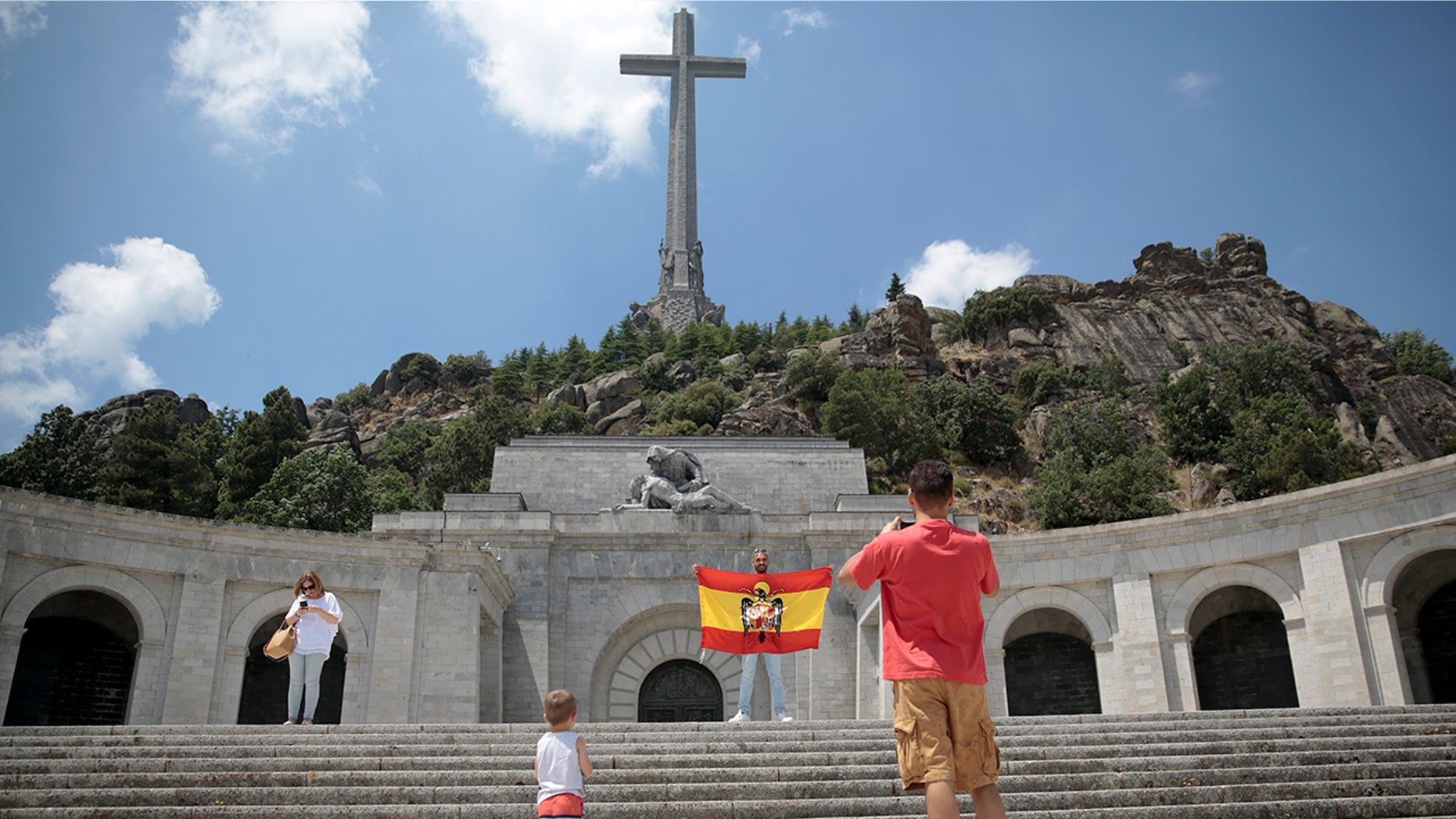 A man poses with a pre-constitutional Spanish flag of the former Spanish dictator Francisco Franco era at the Valley of the Fallen monument near El Escorial, outside Madrid, July 13, 2018.