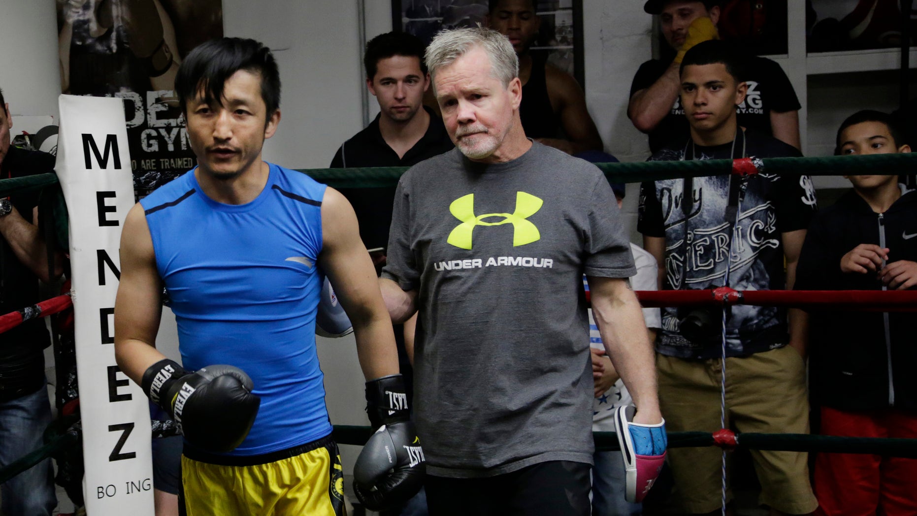 Zou Shiming, left, a two-time Olympic gold medalist and three-time World Amateur Champion from China, exits the ring with trainer Freddie Roach after a workout, Wednesday, June 8, 2016, at Mendez Gym in New York. Zou will be defending his WBO International flyweight title and No. 2 world rating in a 10-round bout against Jozsef Ajtai of Hungary,Saturday, June 11 at Madison Square Garden. (AP Photo/Mark Lennihan)