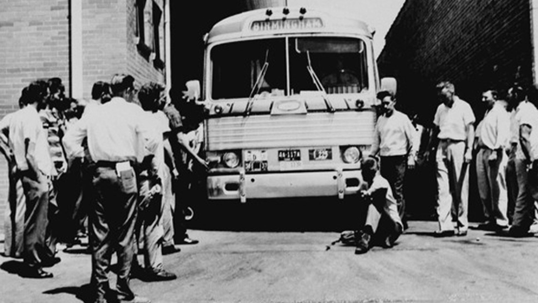 May 14, 1961: An unidentified white man sits in front of a Greyhound bus to prevent it from leaving the station with a load of Freedom Riders testing bus station segregation in Anniston, Ala., as other white men mill around station. The bus was stopped by a flat tire and surrounded by a white crowd outside Anniston, and burned a short time later. The passengers got out without serious injury. (AP)