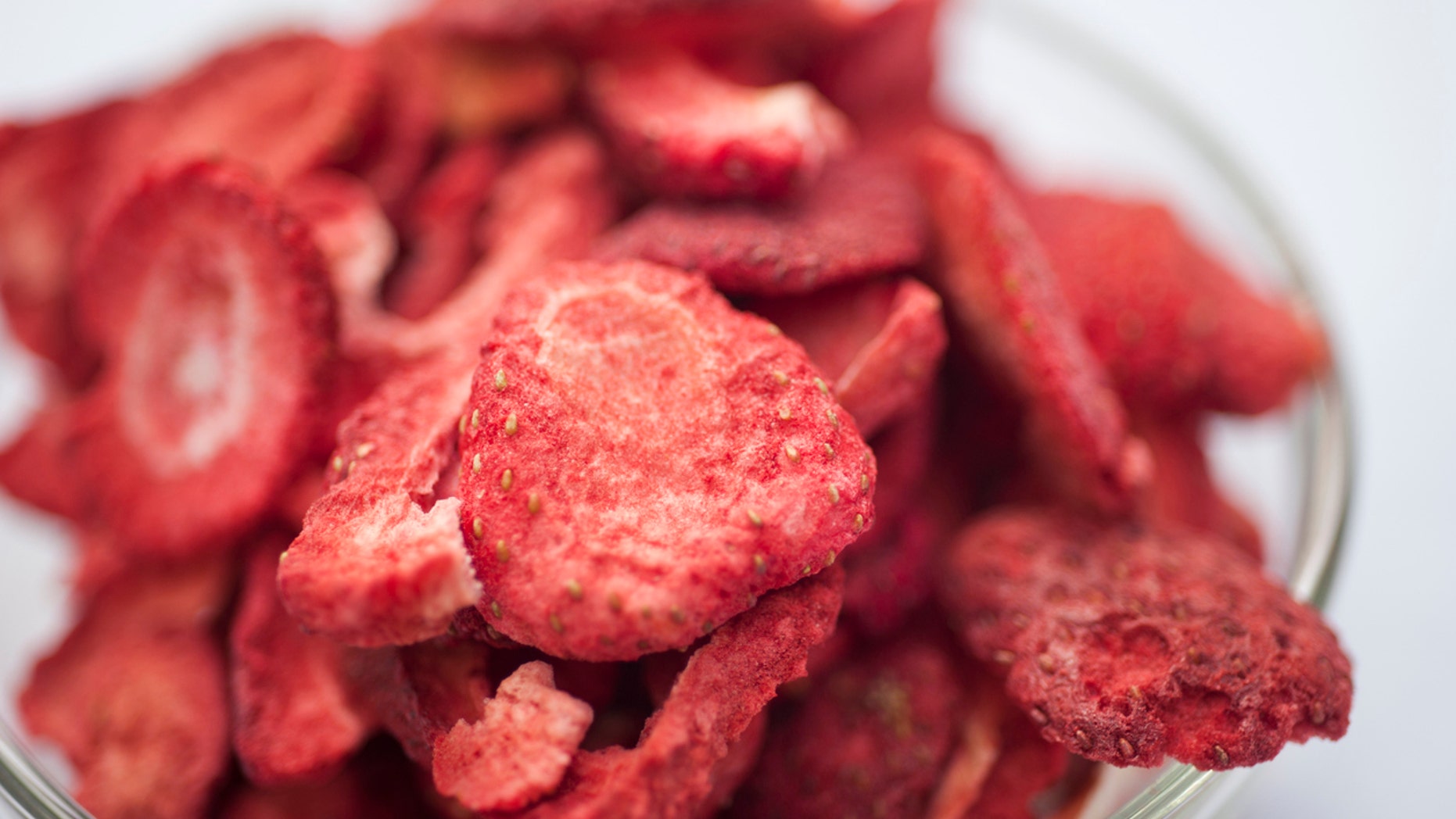 Freeze dired strawberries on a white background in a glass bowl on a sunny day.